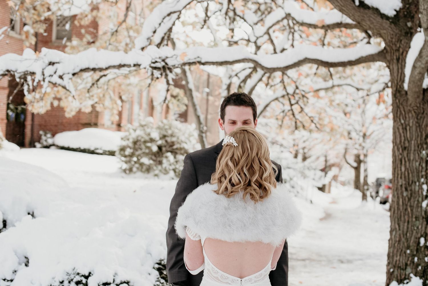 Bride and groom share a romantic moment outdoors in a snowy winter wonderland, bride wearing a white fur shawl.