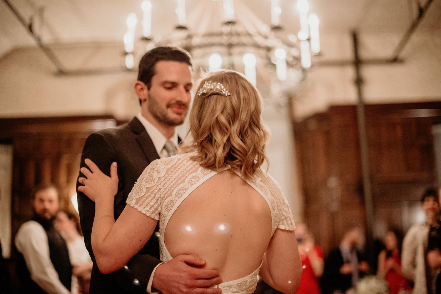 Bride and groom share their first dance under a chandelier at an elegant wedding reception.