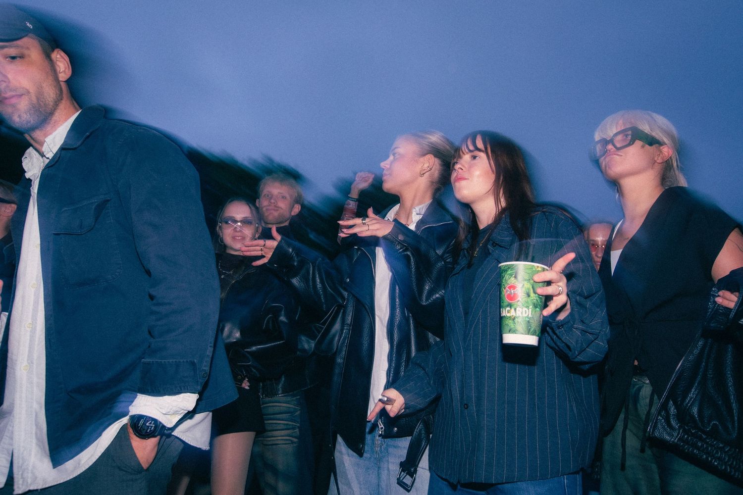 Group of festival attendees dancing and socializing at an outdoor nighttime music event.