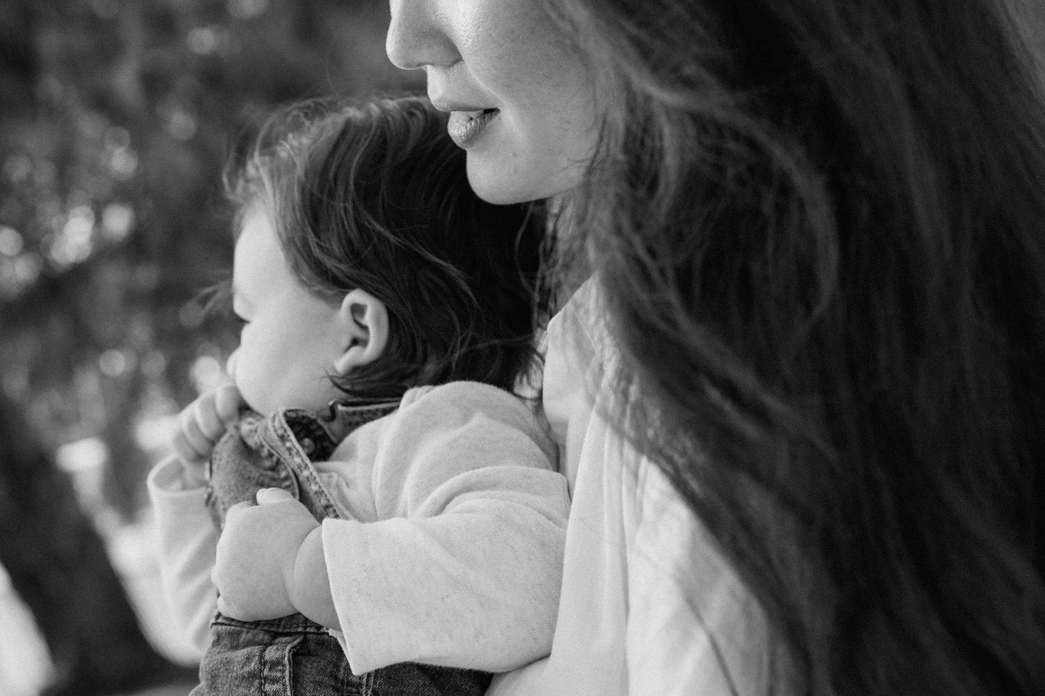 Black and white portrait of a mother with long hair holding her young toddler.