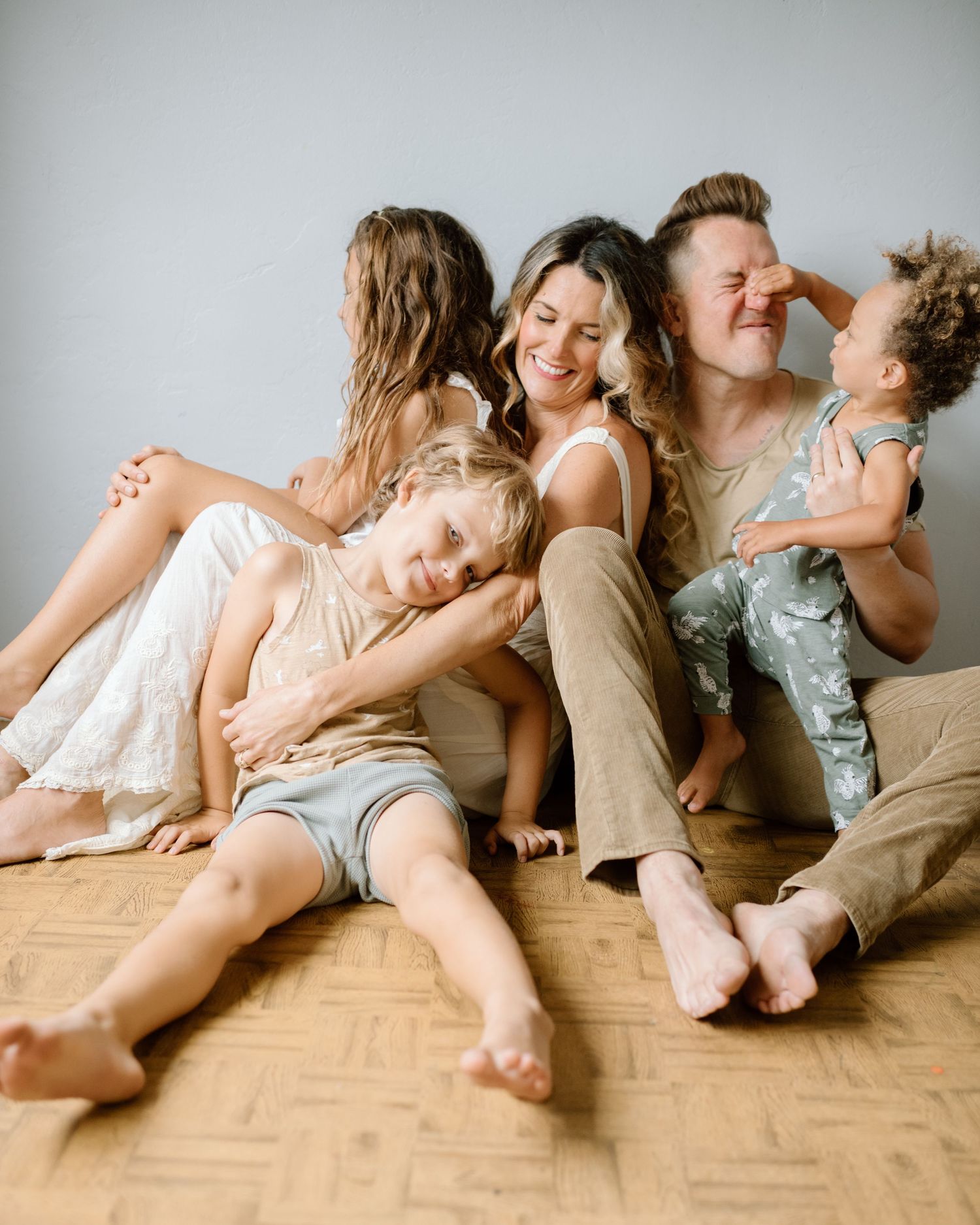 Family snuggles on floor during at home family photoshoot in San Diego.