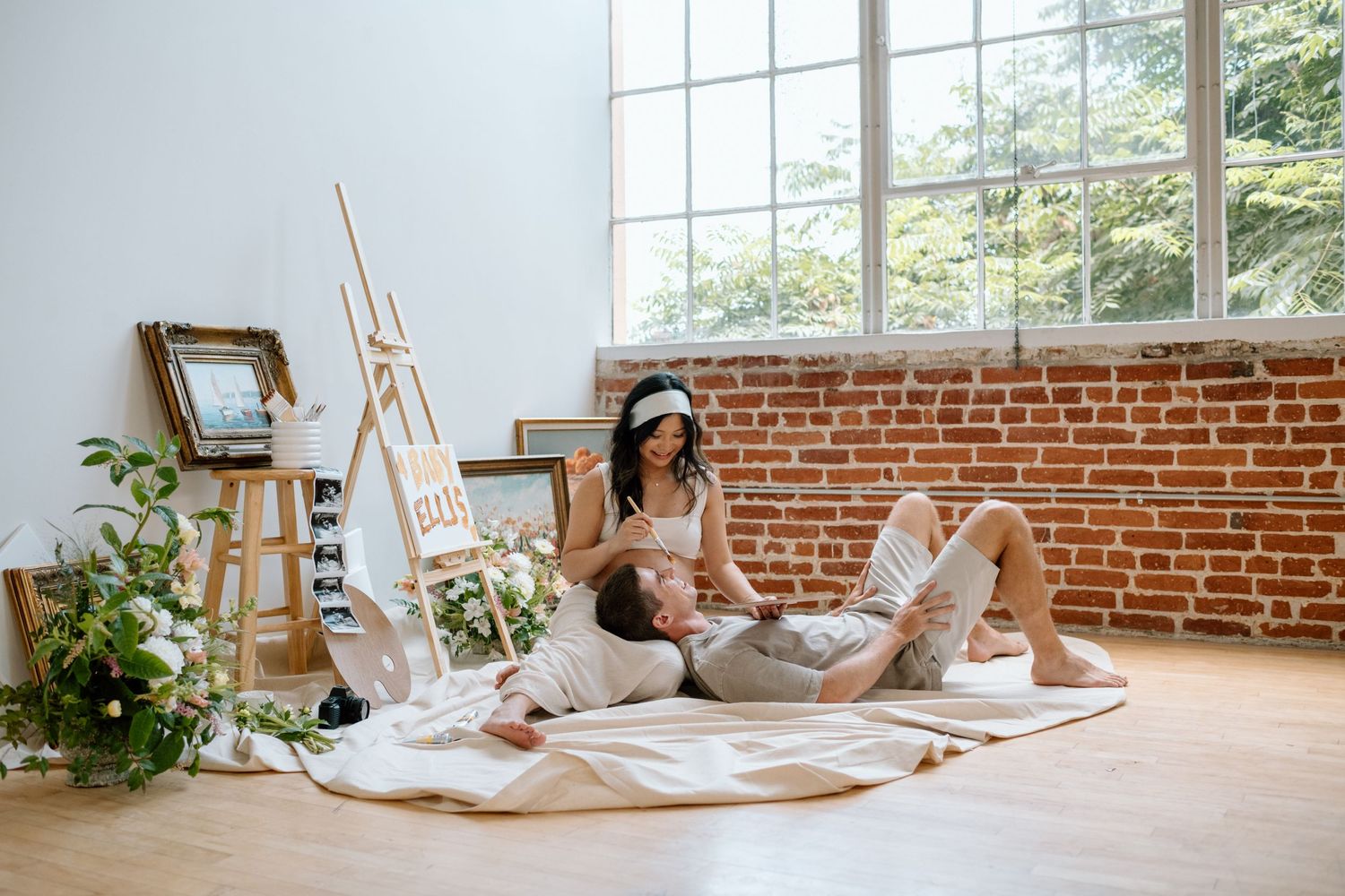 Pregnant woman teases husband while lying down during maternity photoshoot in a San Diego studio.