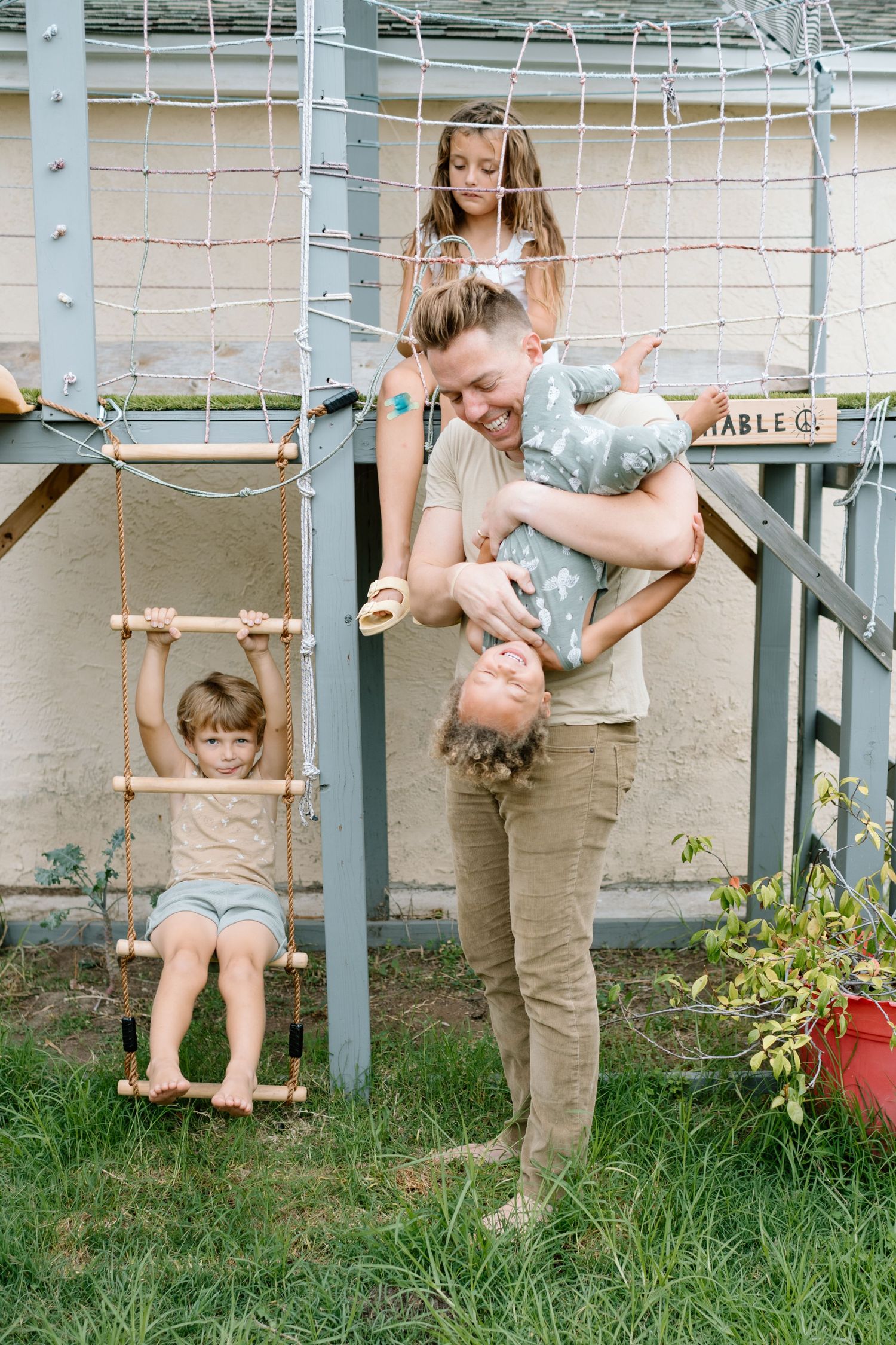 Dad plays with three kids on playhouse during at home family photoshoot in San Diego.