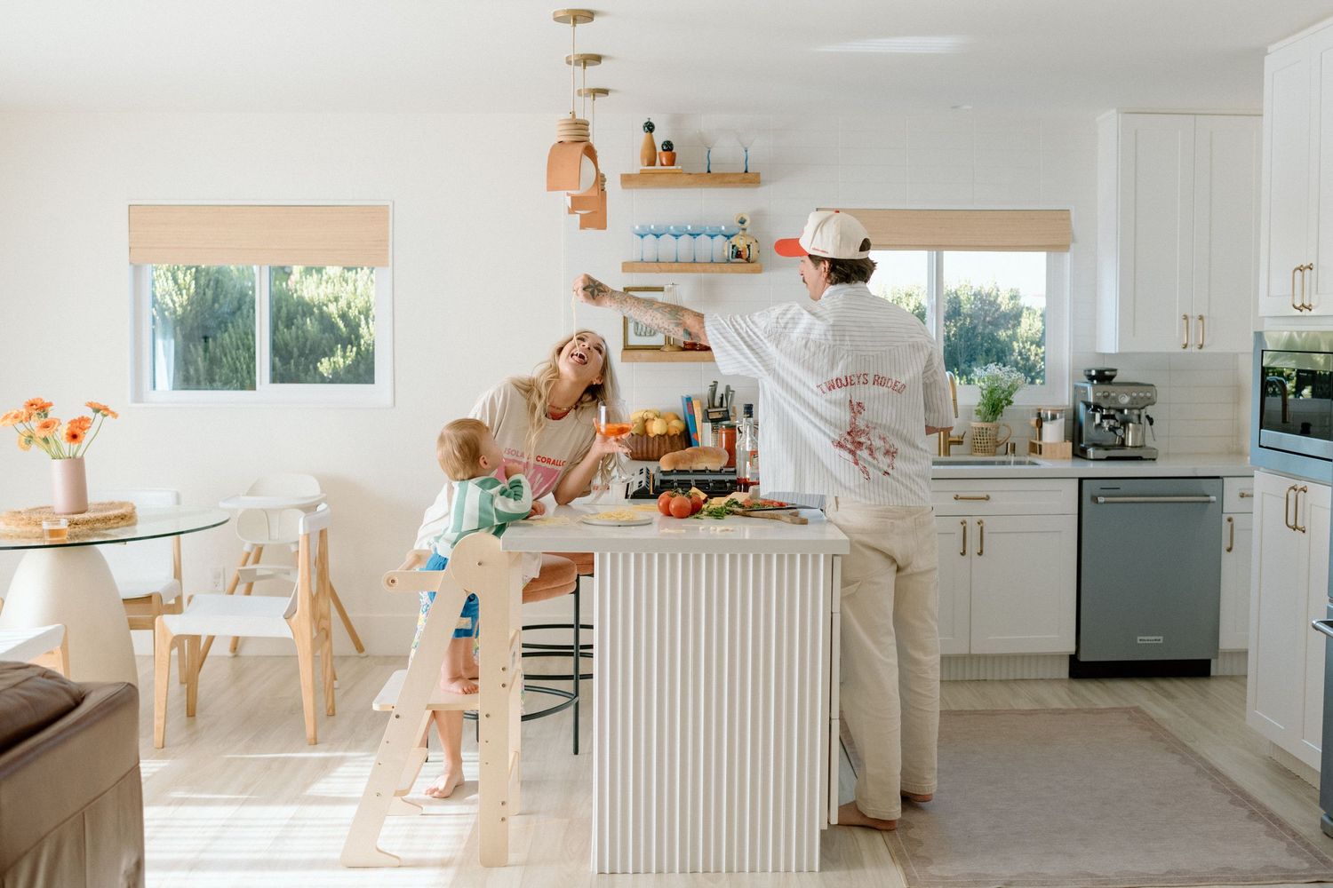 Family cooking together in a bright white modern kitchen with children at the island counter.