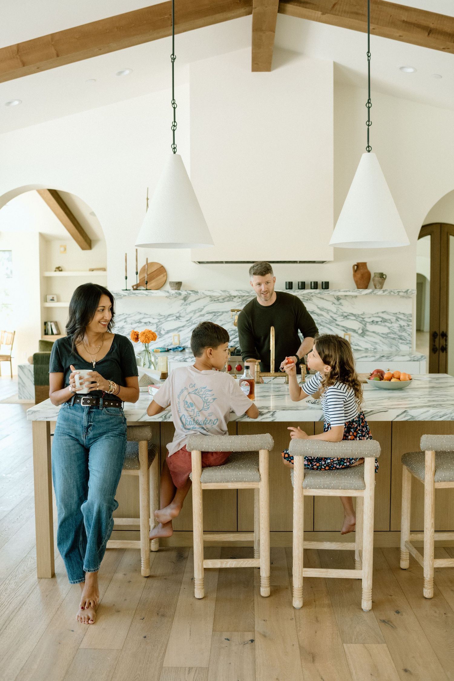 Happy family of four gathers around a kitchen island in a bright modern home.