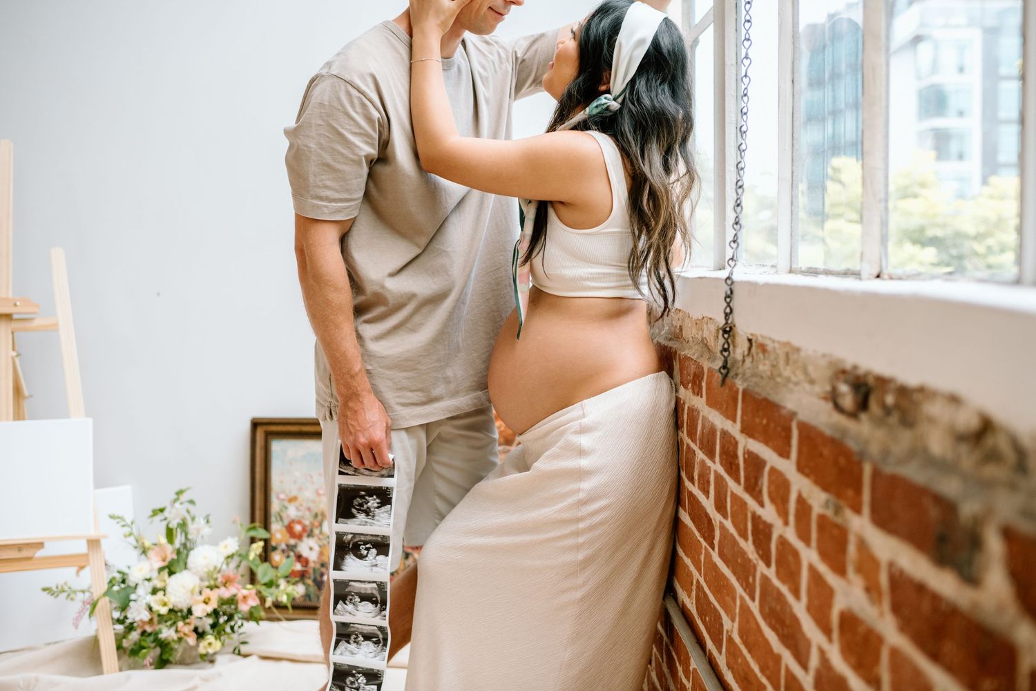 Pregnant woman reaches up to touch man's face during maternity session a San Diego studio