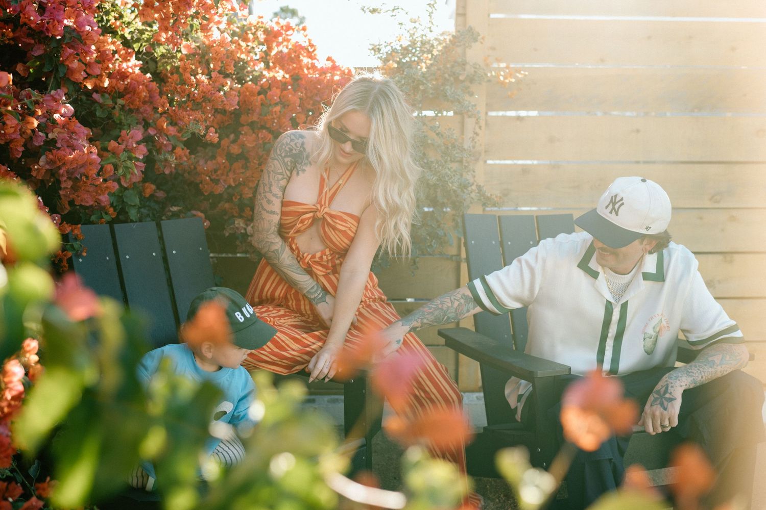 Couple sitting outdoors surrounded by vibrant blooming flowers in sunlight.