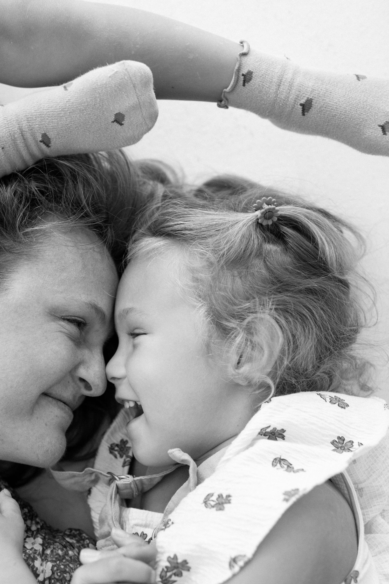 Black and white photo of mother and young daughter laughing together face to face.