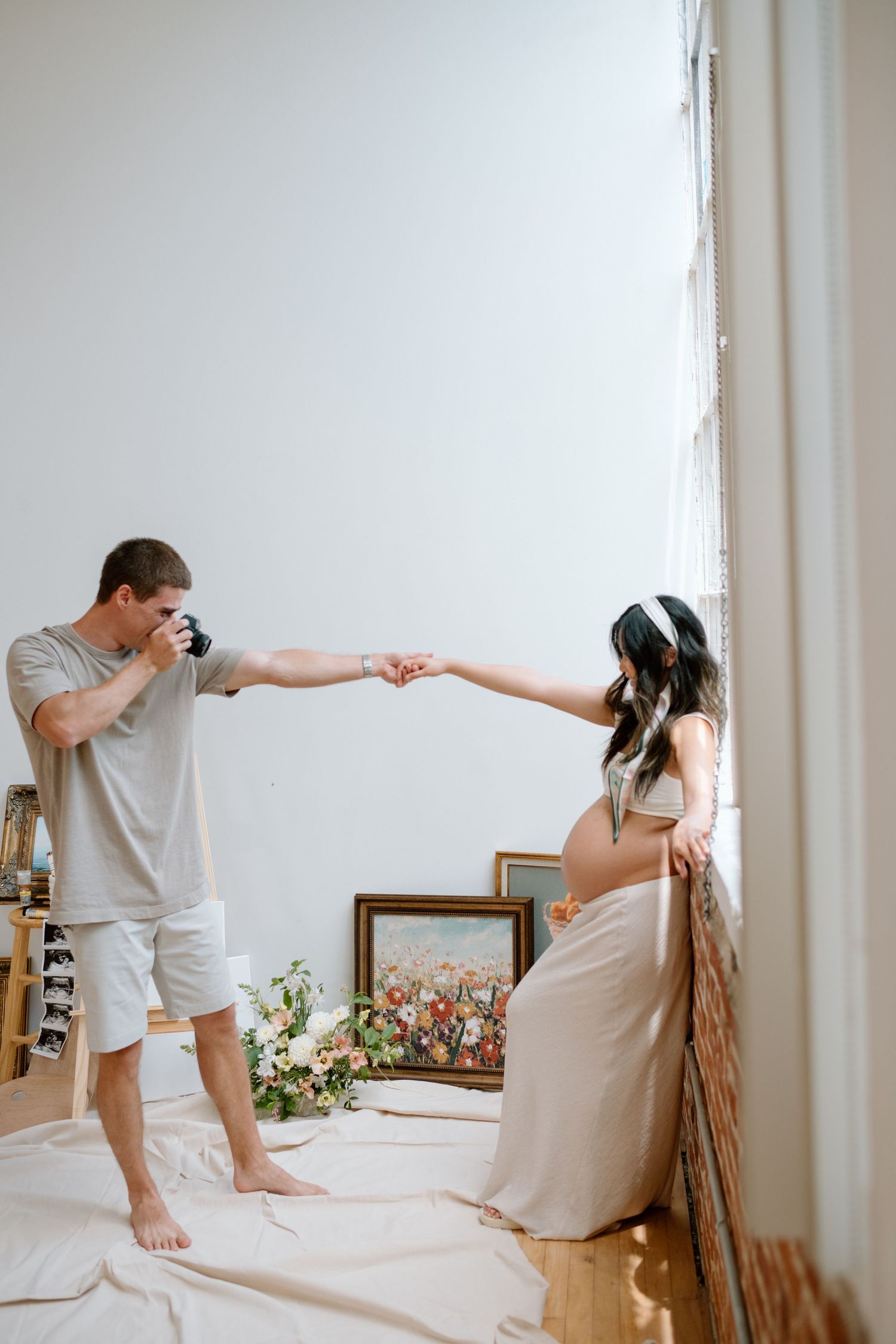 Man takes picture of pregnant wife during maternity photoshoot in a San Diego studio.