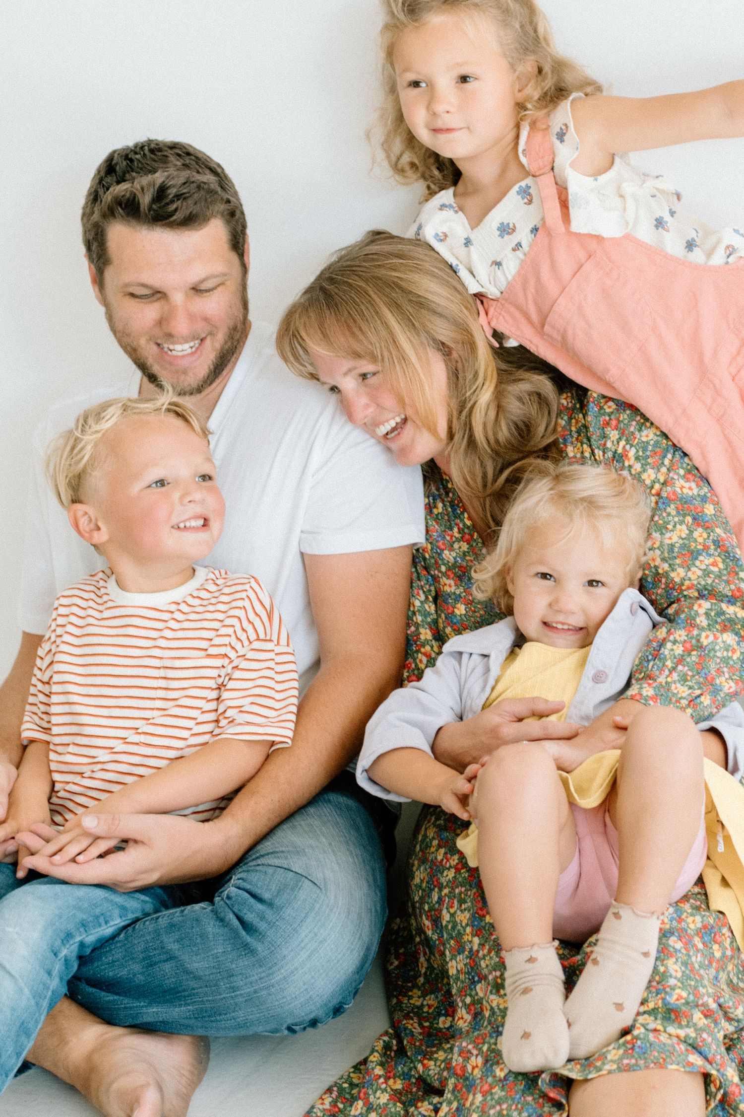 Smiling family of five cuddling together on floor with parents and three young children.