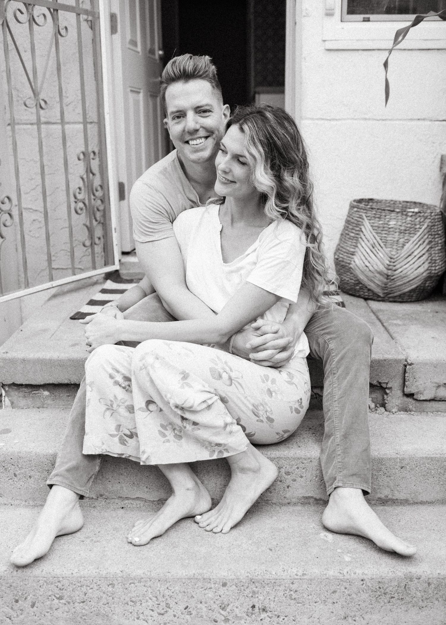 Mom and dad snuggle on porch during at home family photoshoot in San Diego.
