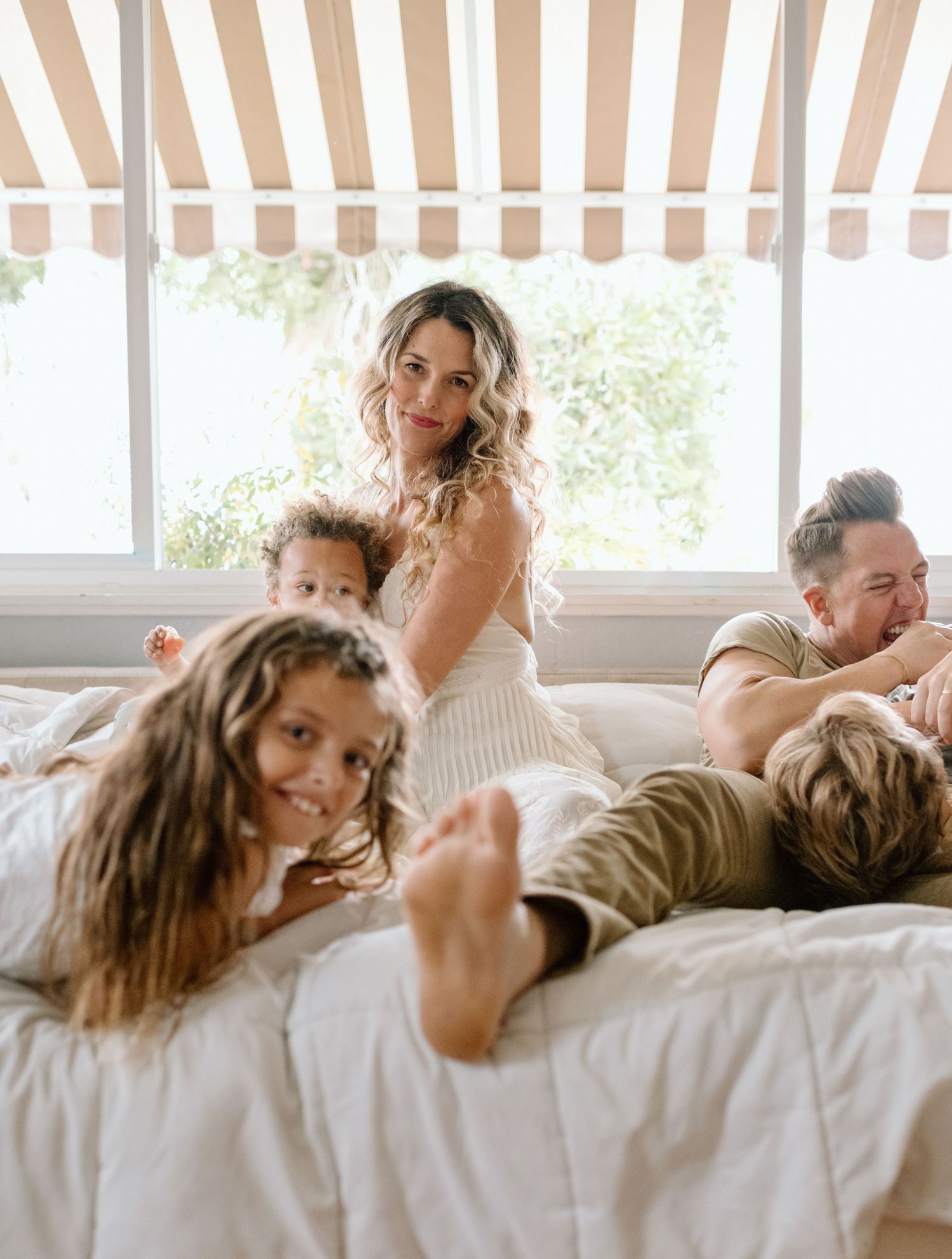 Family wrestling on couch during at home family photoshoot in San Diego