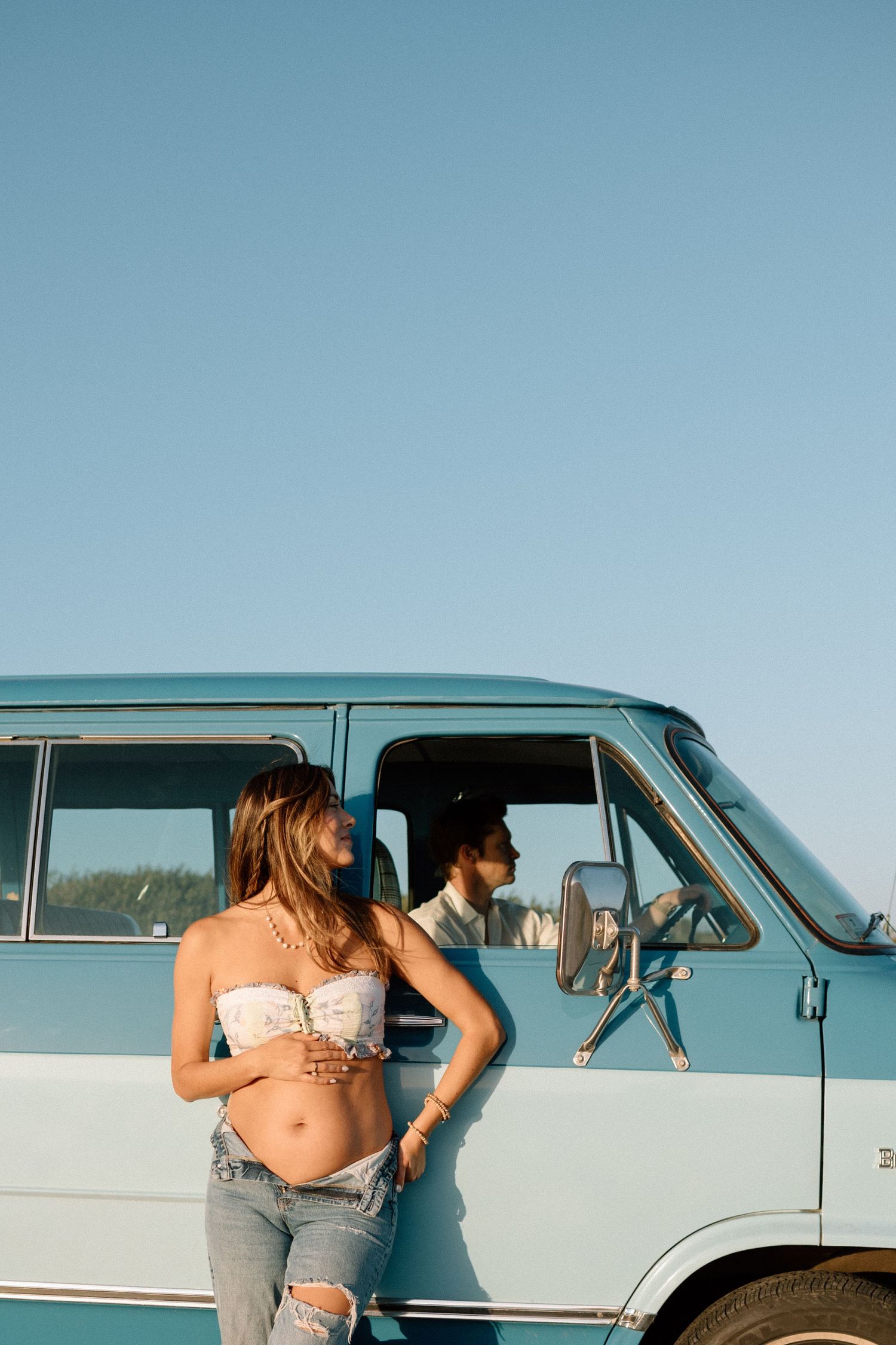 A retro blue and white van parked under clear blue skies on a summer day.