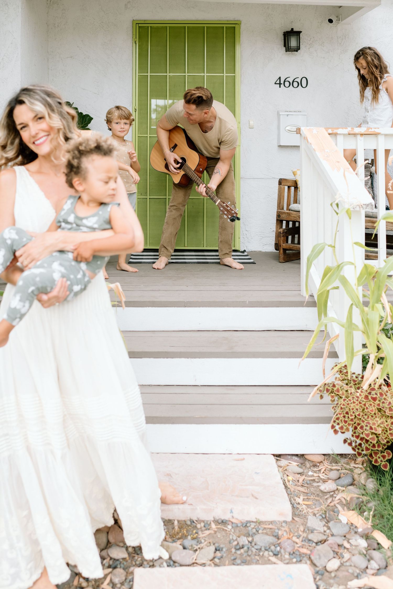 Family sings and dances on front porch during at home family photoshoot in San Diego.