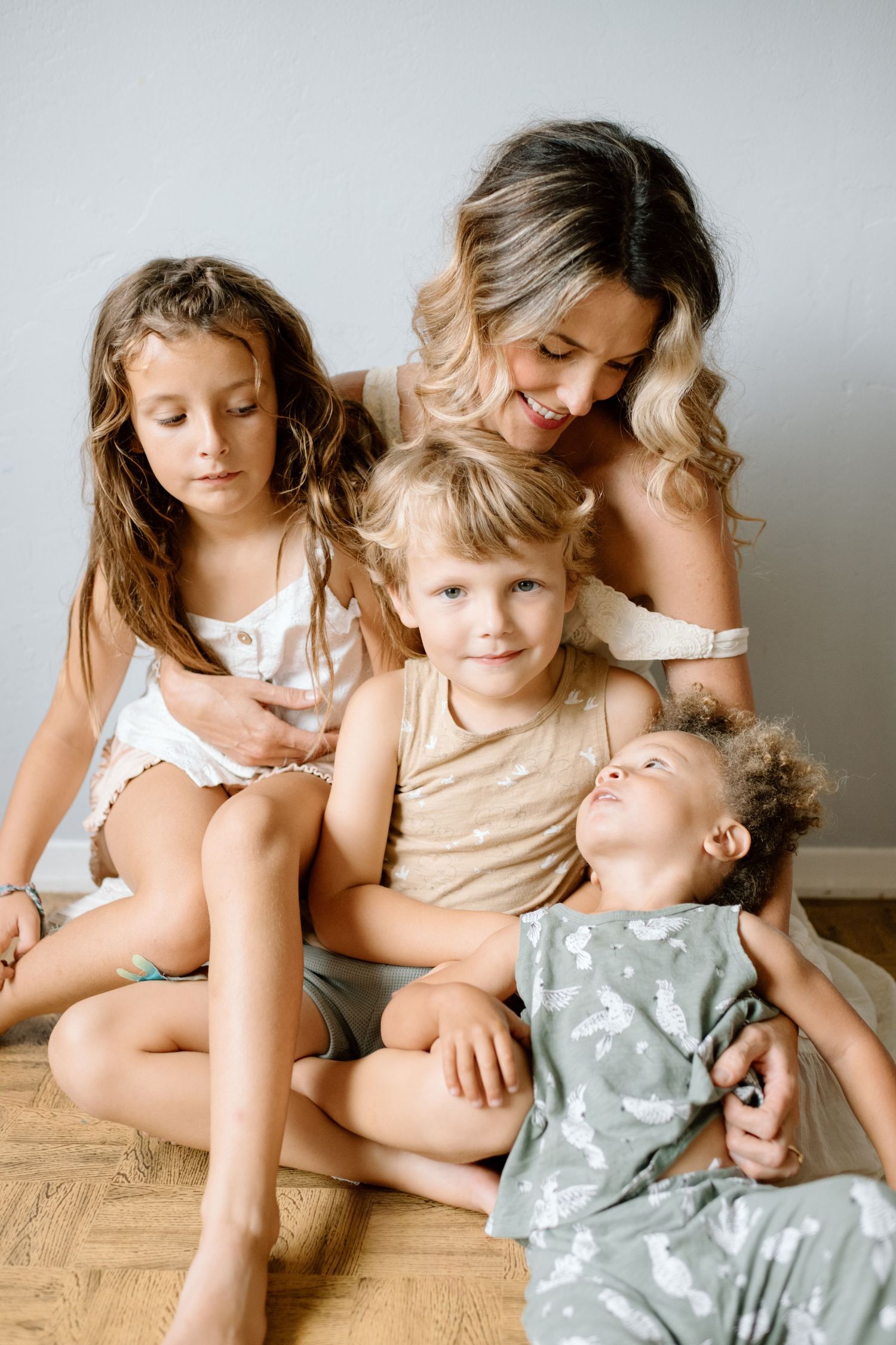 Mom cuddles with kids during at home family photoshoot in San Diego.