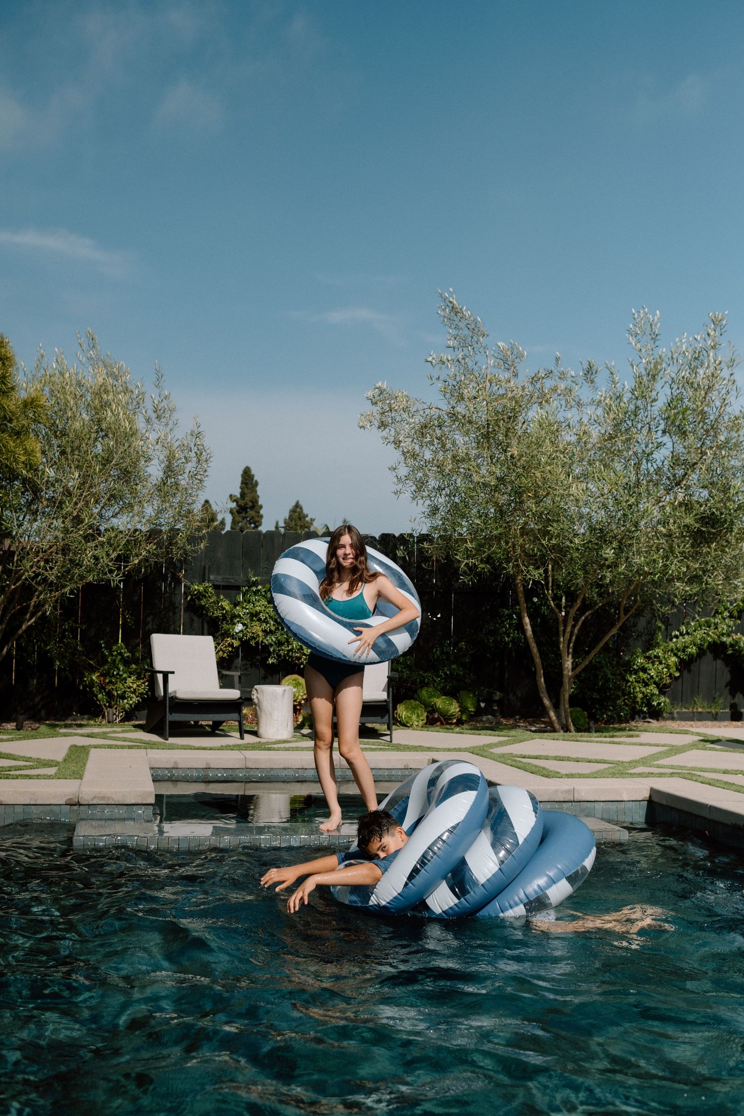Summer pool fun with blue striped floaties in a backyard swimming pool on a sunny afternoon.
