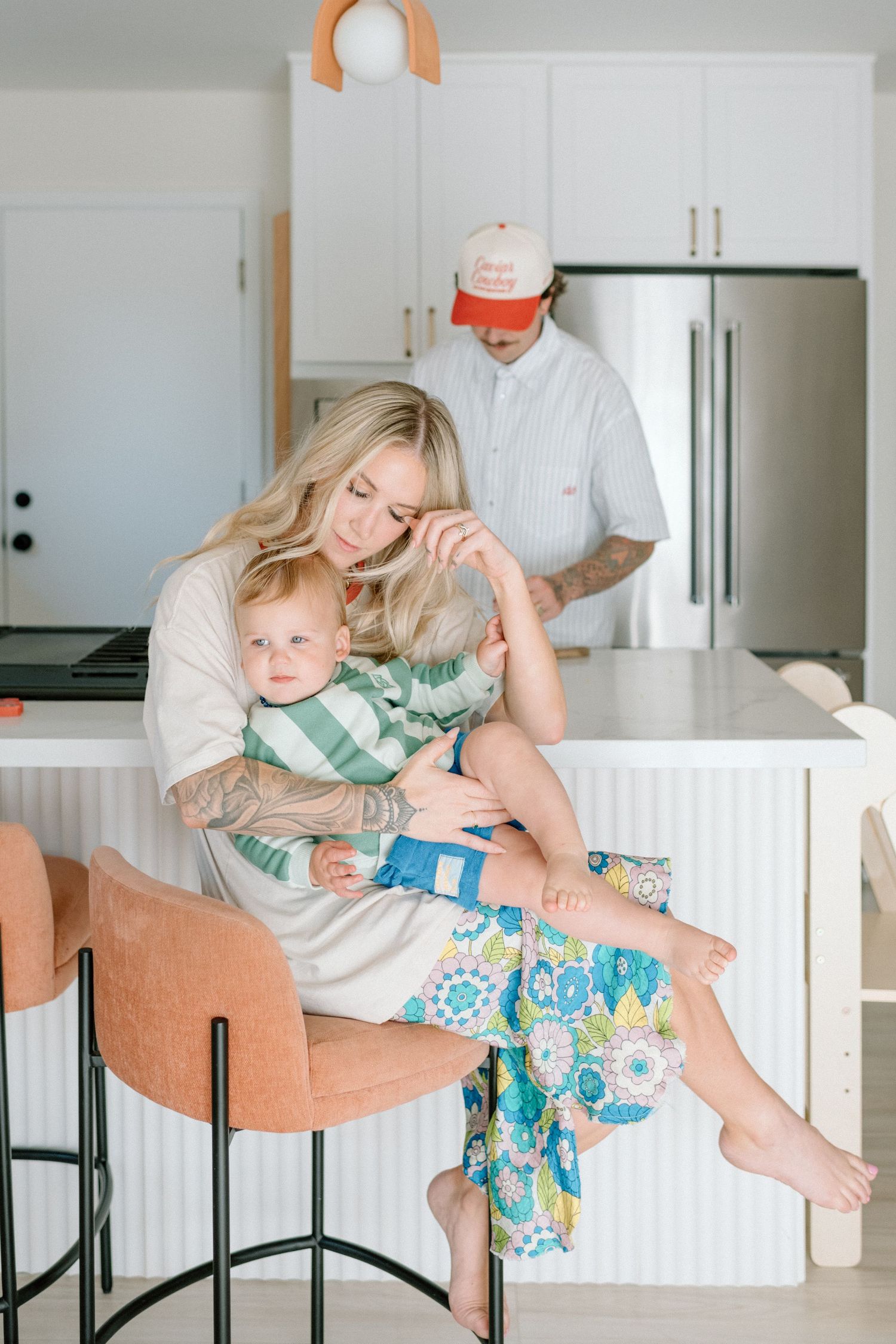Four connected images show playful moments on a beige counter stool in a bright white kitchen setting.