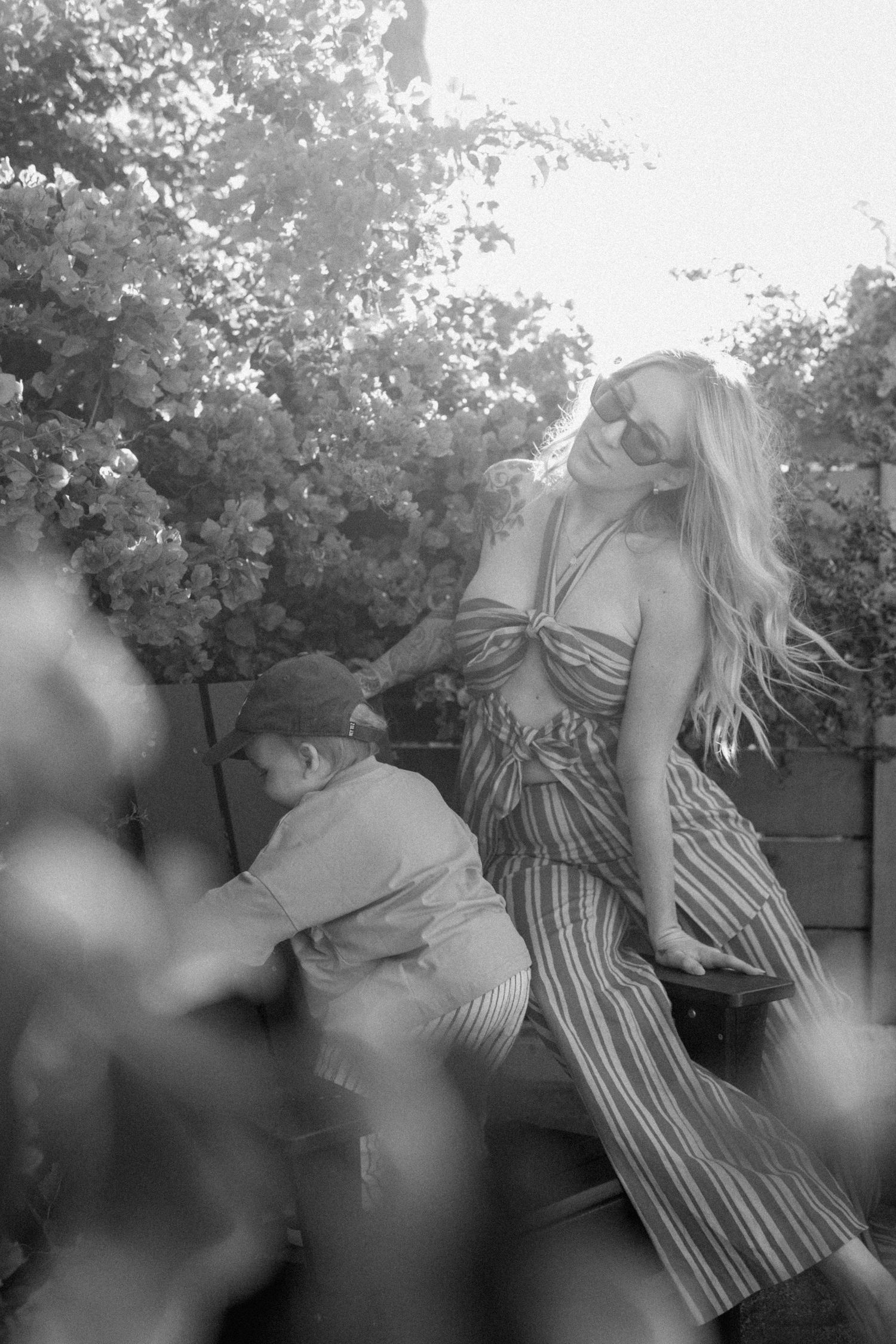 A black and white series of dreamy outdoor portraits showing a person in a striped dress among foliage.