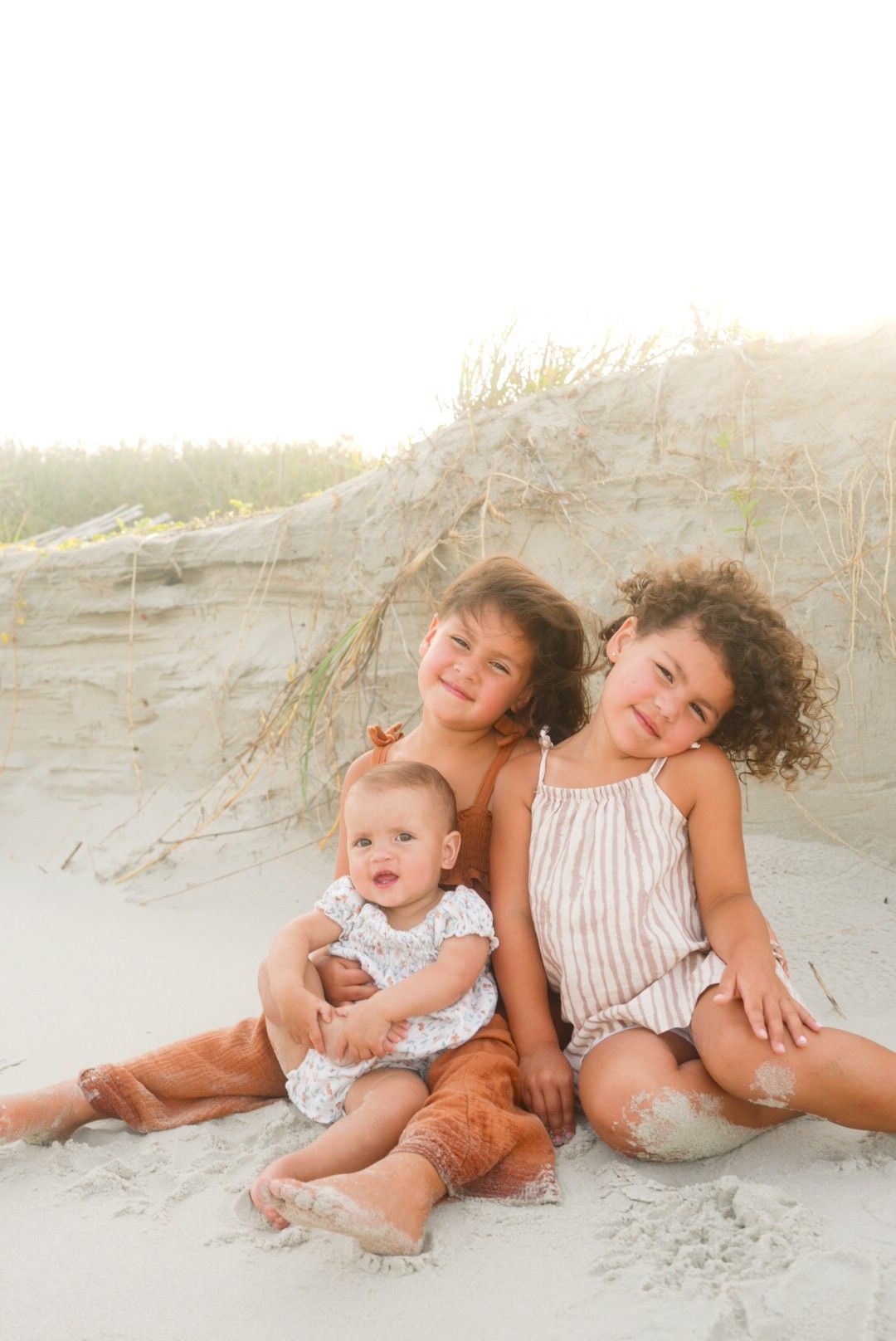 Siblings sitting on the beach during a photoshoot in South Carolina.