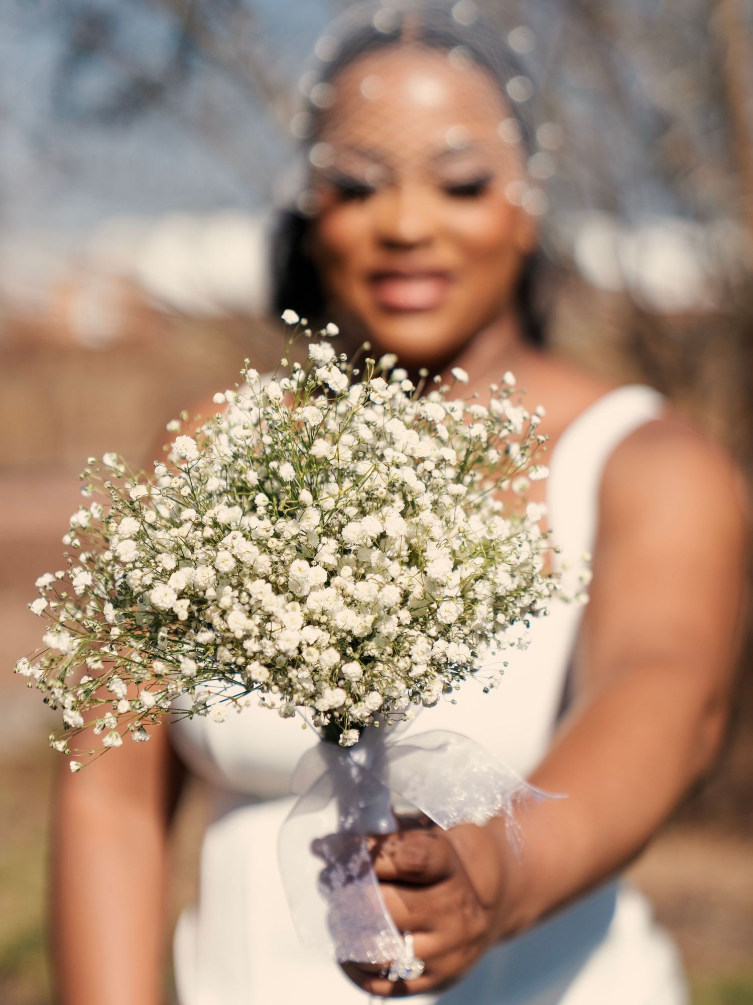 Bride in white dress holds bouquet of white baby's breath flowers on her wedding day. Wedding Photography