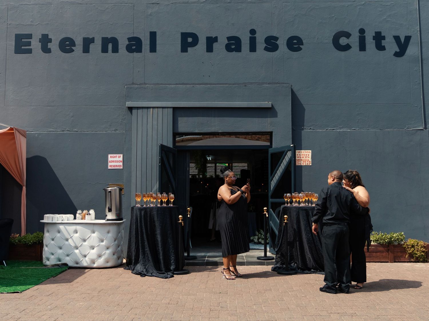 Guests arriving at Eternal Praise City wedding venue with champagne display and white furniture outside.