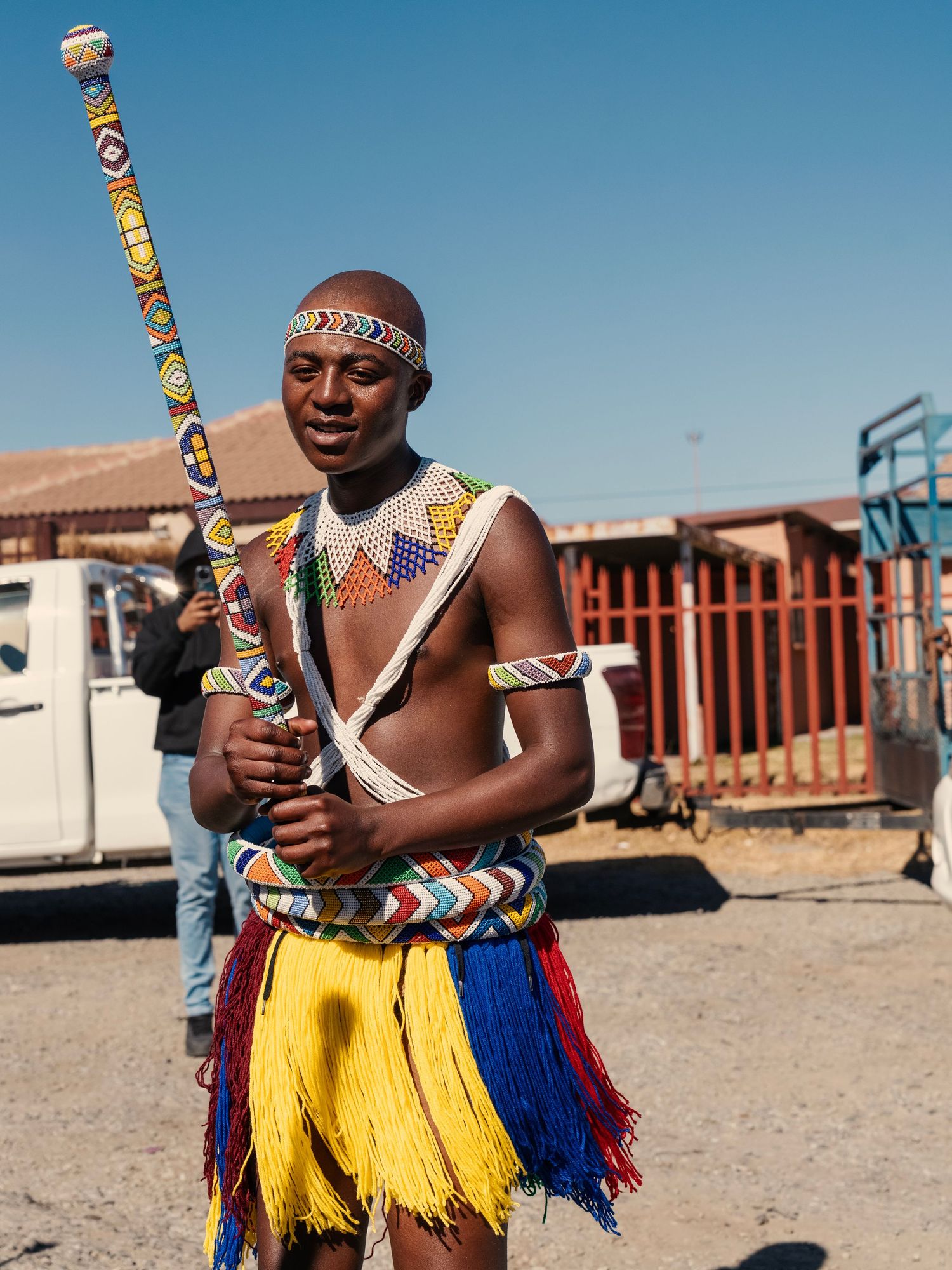 Young man performing in vibrant traditional Zulu cultural attire with colorful fringe skirt and beaded ornaments. Event Photography