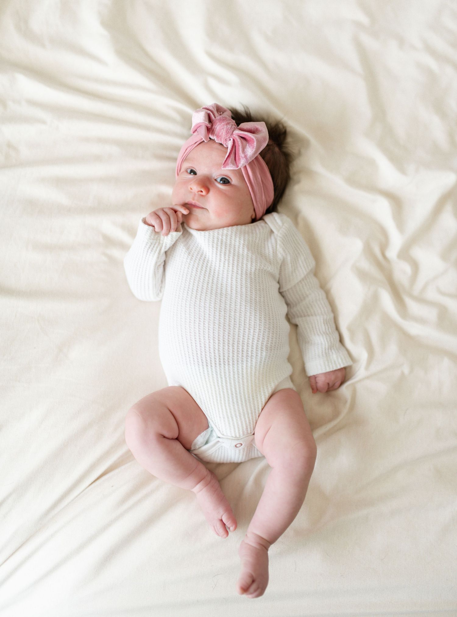 Professional ofallon newborn photographer. Picture of newborn laying on bed.