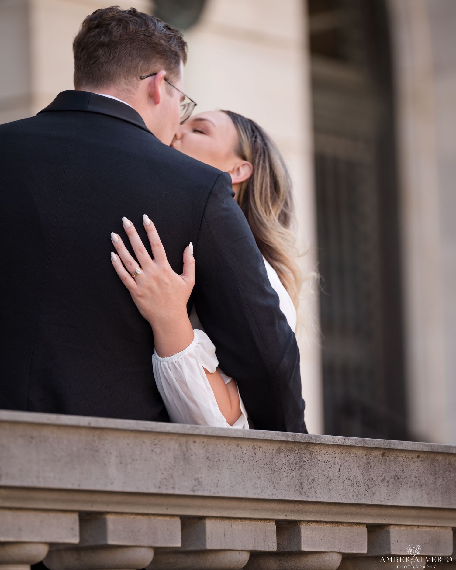 A couple shares a romantic embrace on a stone balcony during a tender moment together.