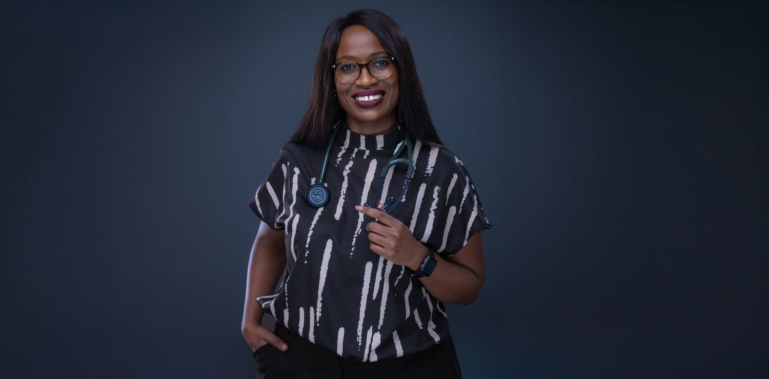 A person wearing a black and white striped shirt laughs joyfully against a dark background.