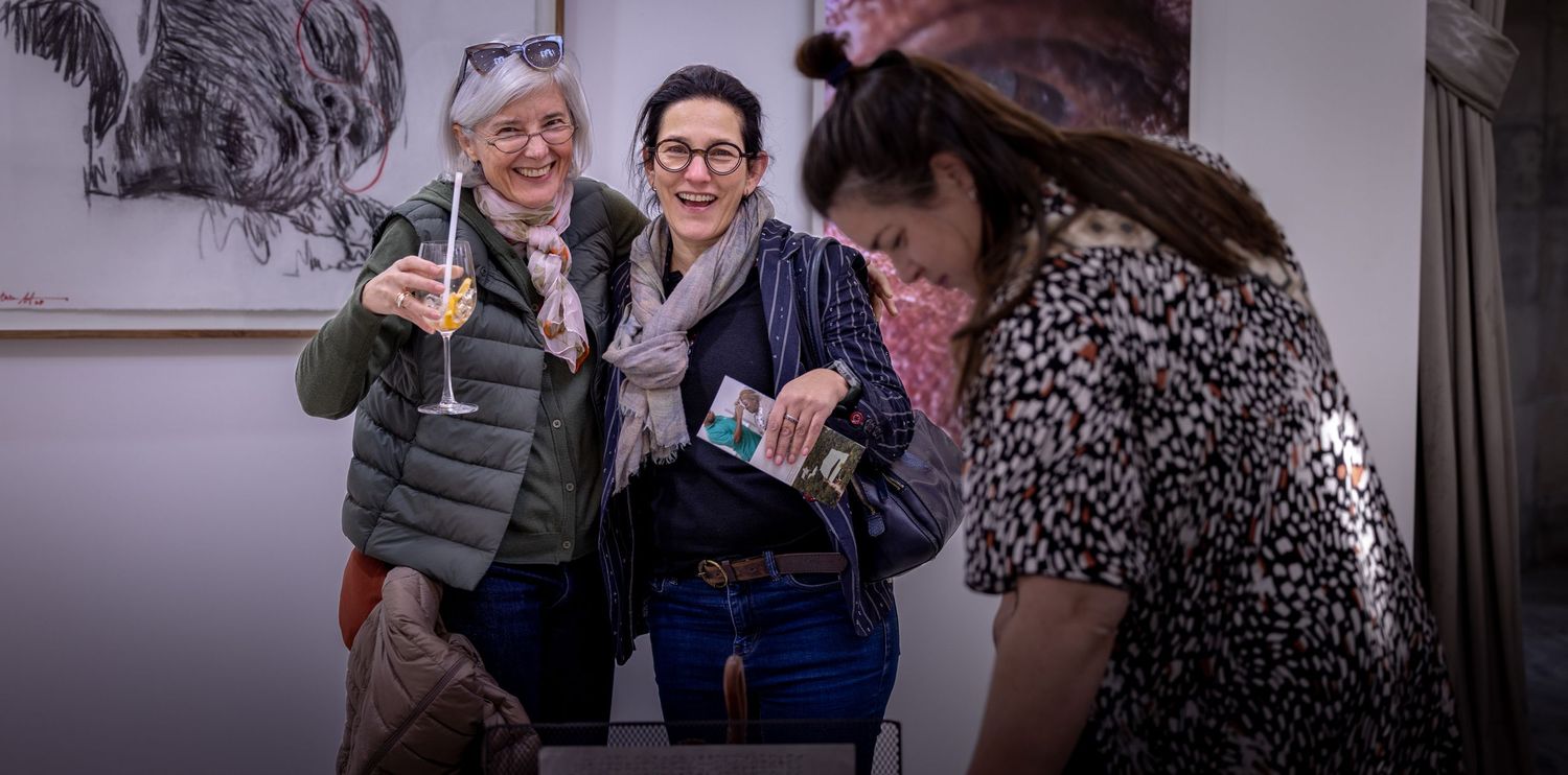 Three people sharing drinks and laughing together at a social gathering.