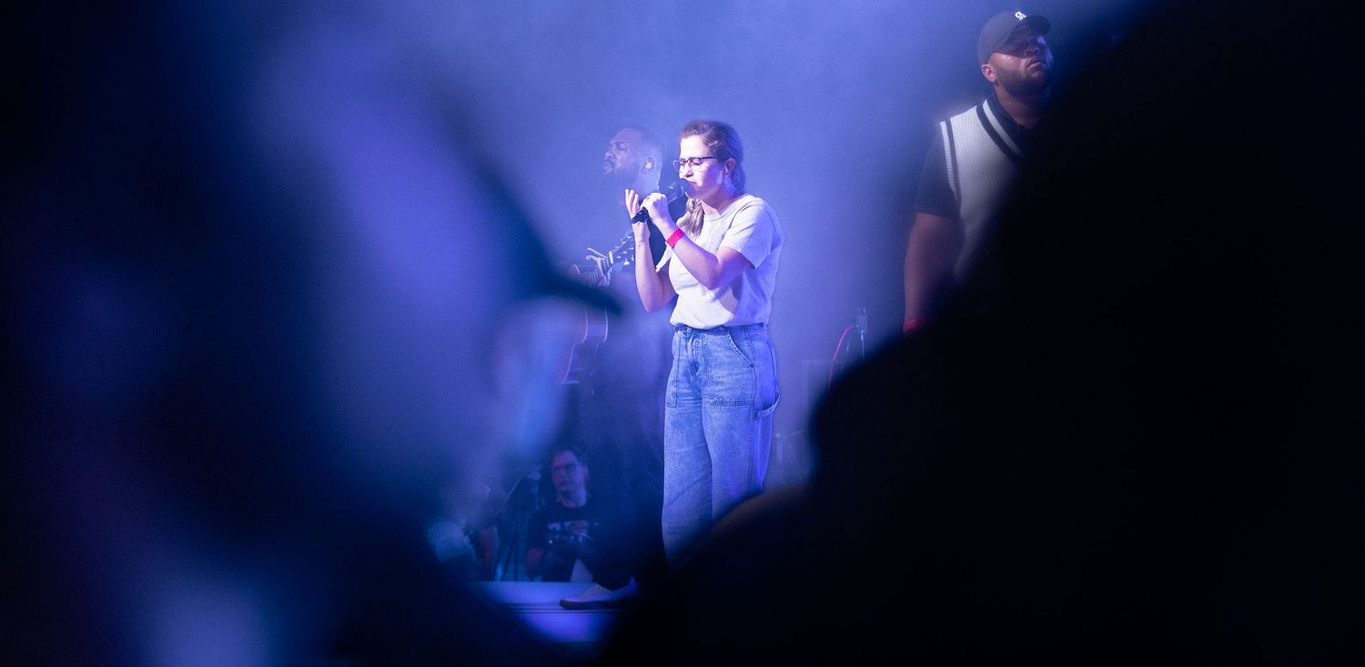 A performer stands on stage illuminated by dramatic blue lighting during a concert performance.