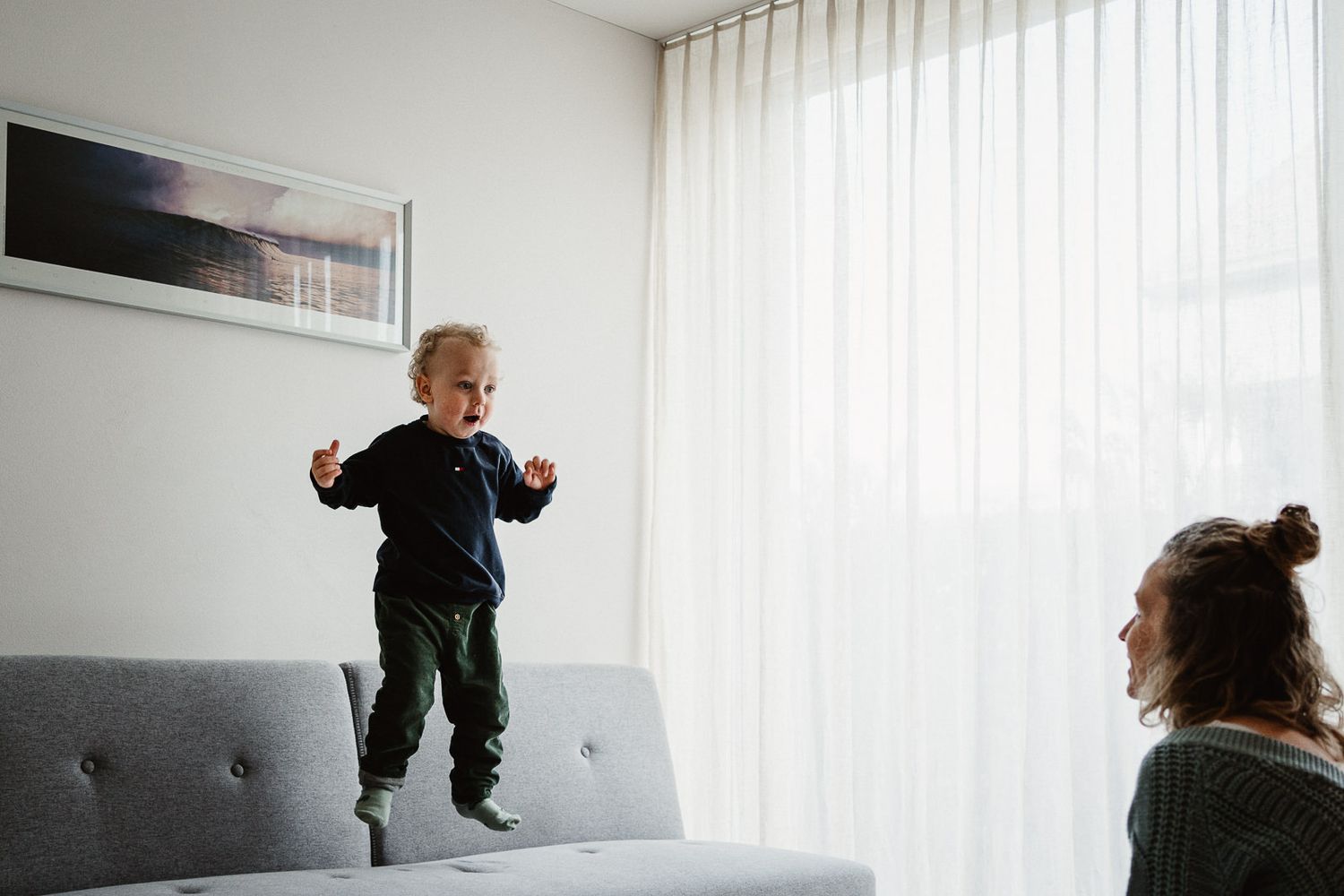 Hüpfendes Kind auf Sofa mit Mama_natürliche Familienfotografie Stadt Bern und Umgebung