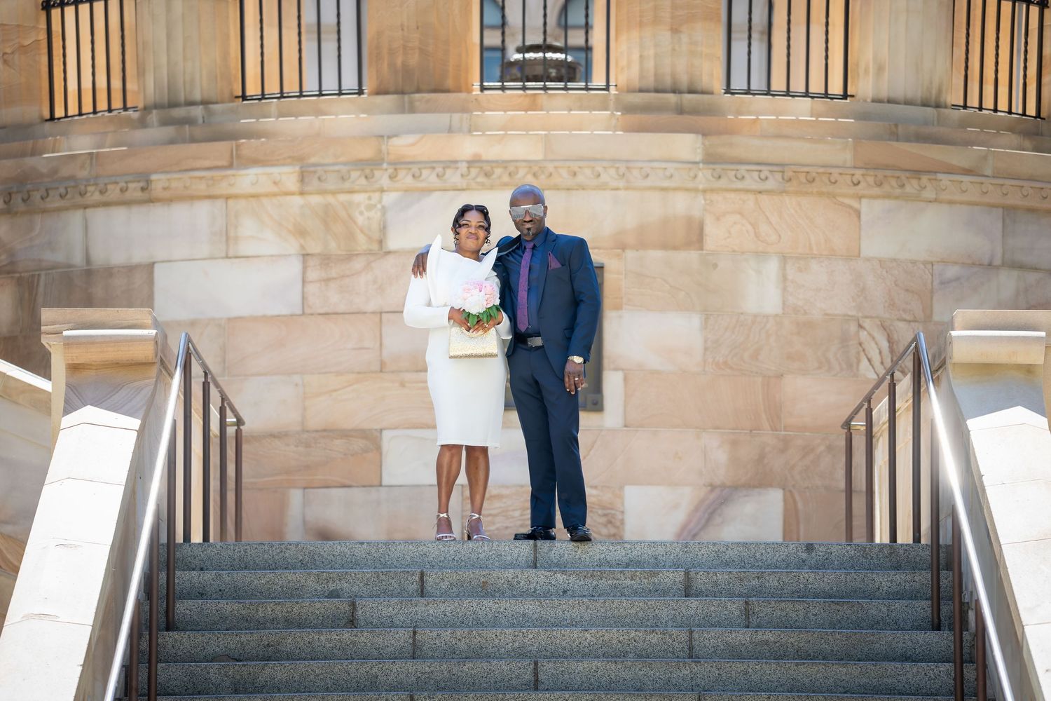 A couple poses on grand stone steps for wedding photos in multiple similar shots showing different angles and poses.