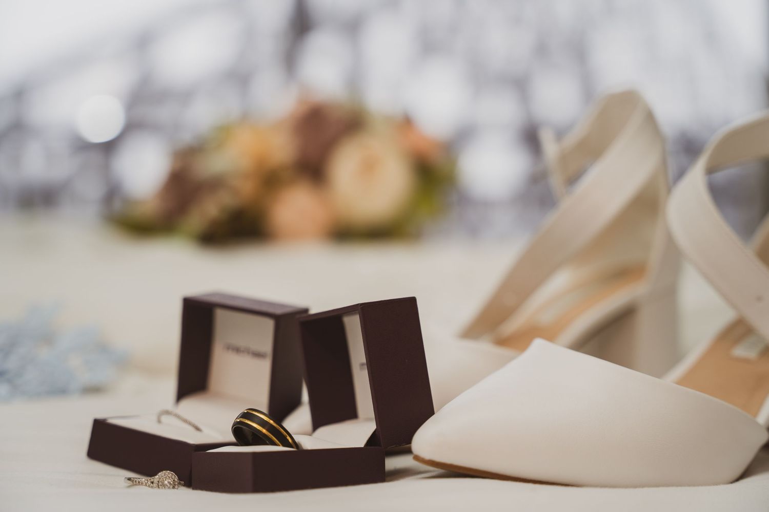 Elegant wedding shoes and jewelry arranged artistically on a light marble surface for bridal details photography.