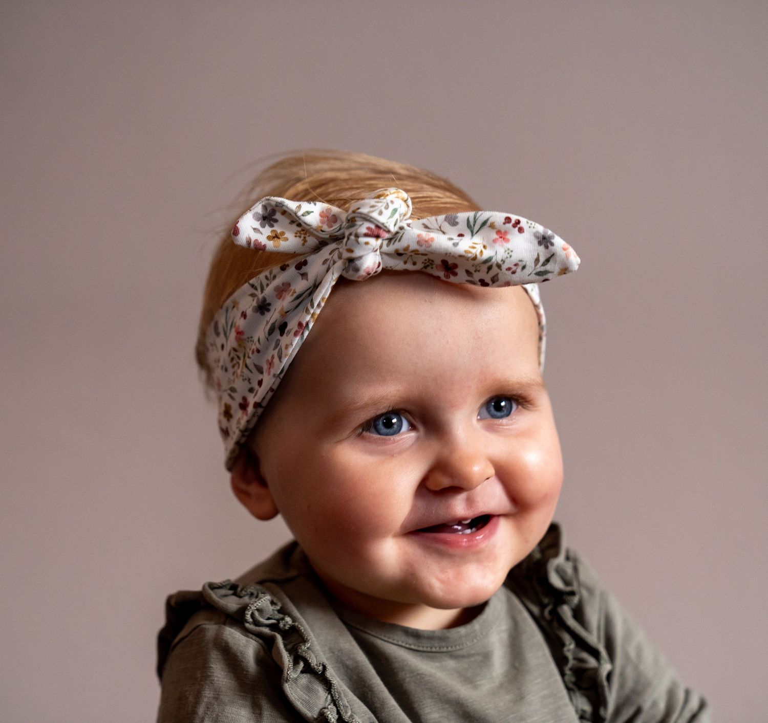 Baby met een vrolijke strik op haar hoofd – helemaal klaar voor haar fotoshoot.