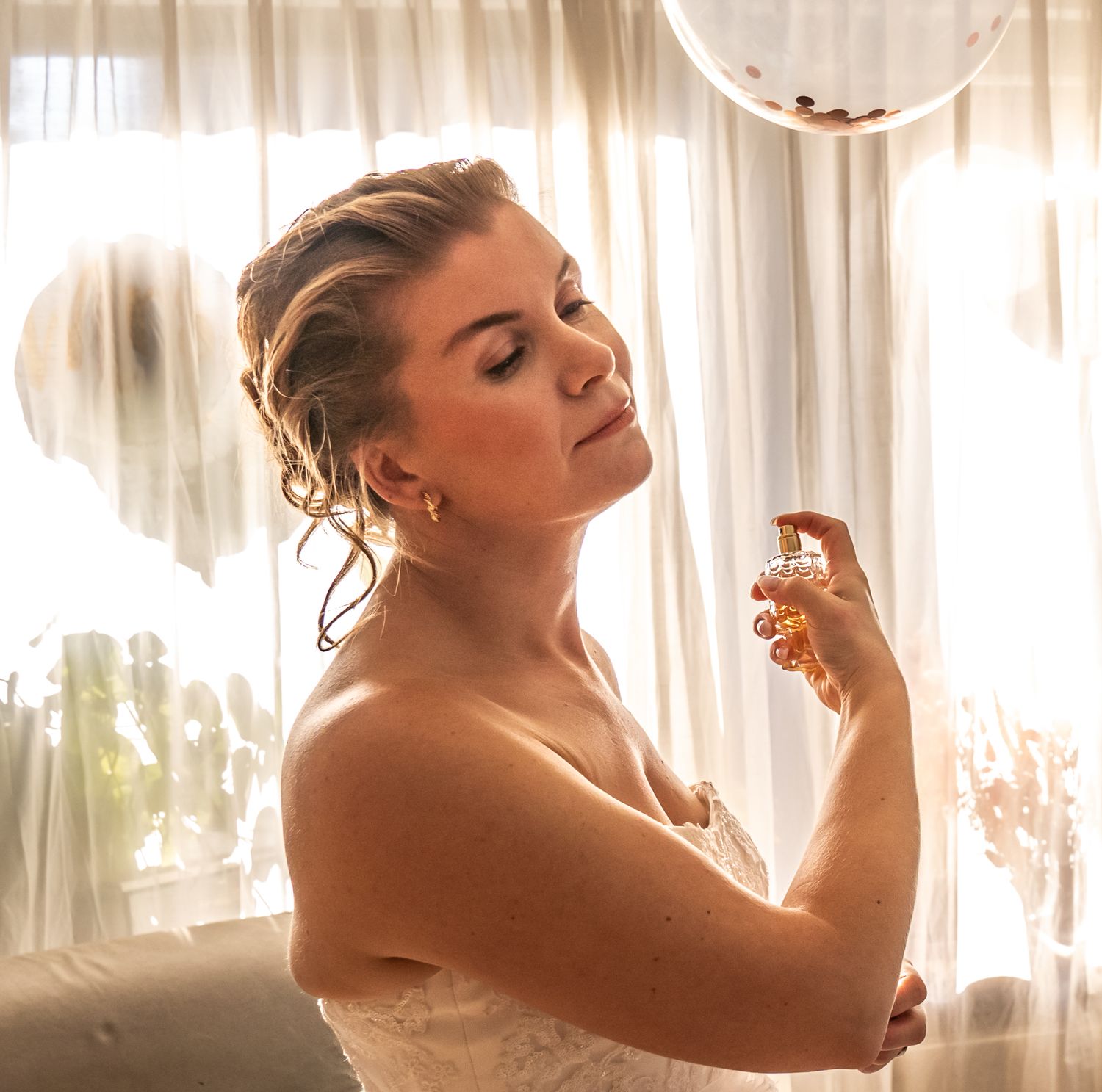 Bruid in de make-up terwijl de zon door het gordijn piept – helemaal in haar element.