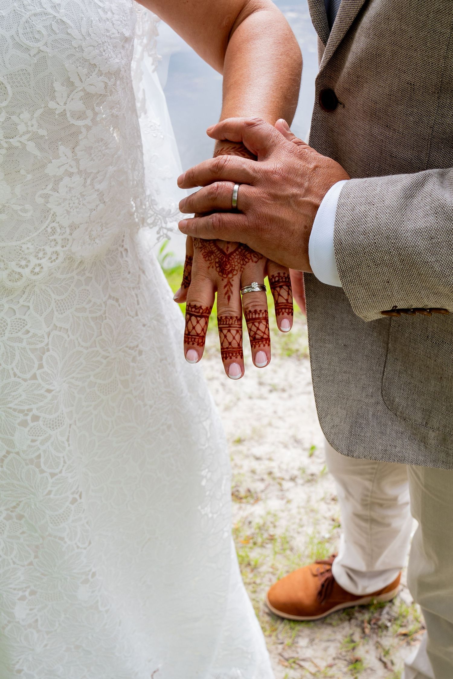 Close-up van de handen van een bruidspaar met henna en trouwringen, symbolisch en liefdevol moment.