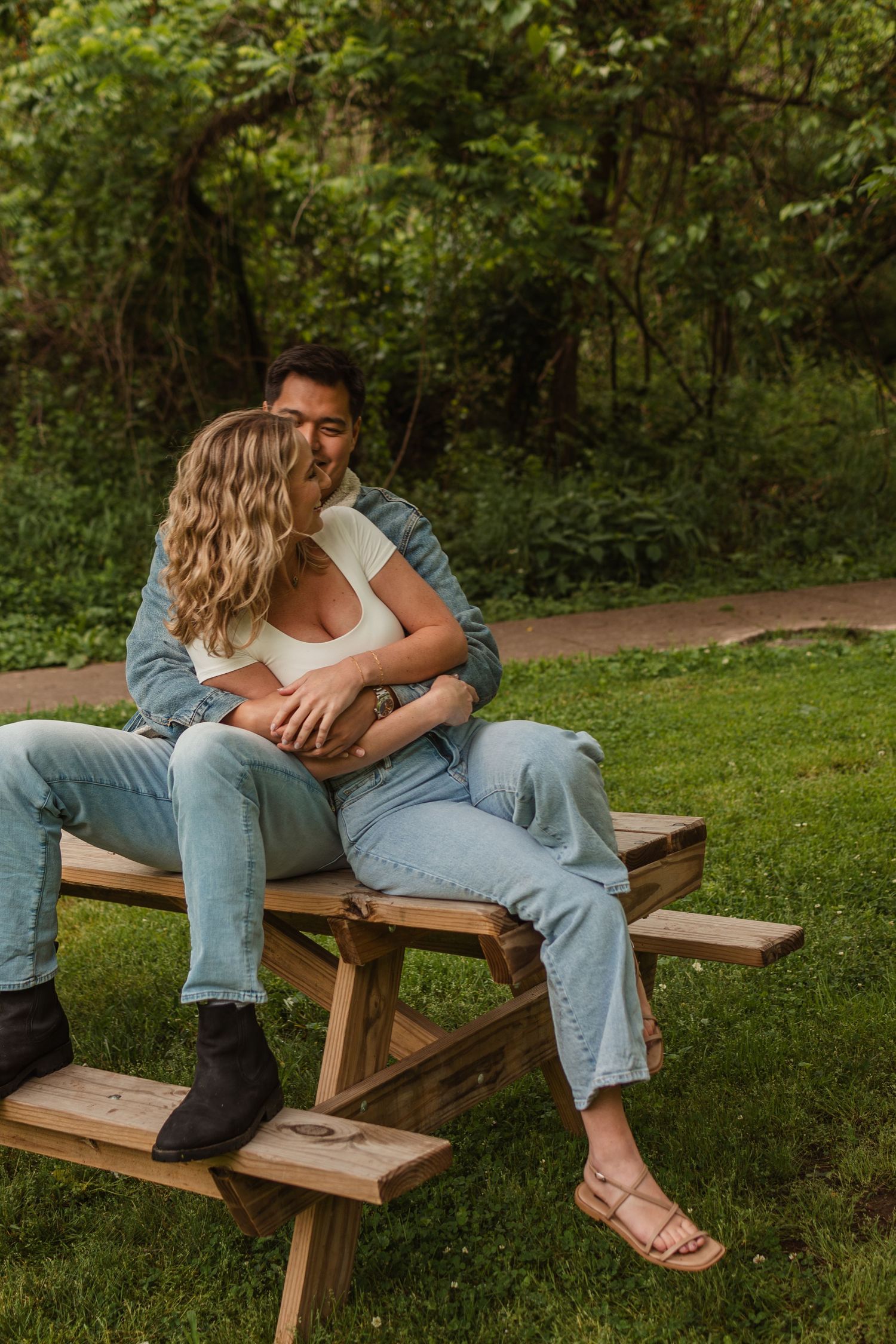 Outdoor couple session in East Nashville, Tennessee featuring a relaxed moment on a wooden bench surrounded by greenery.