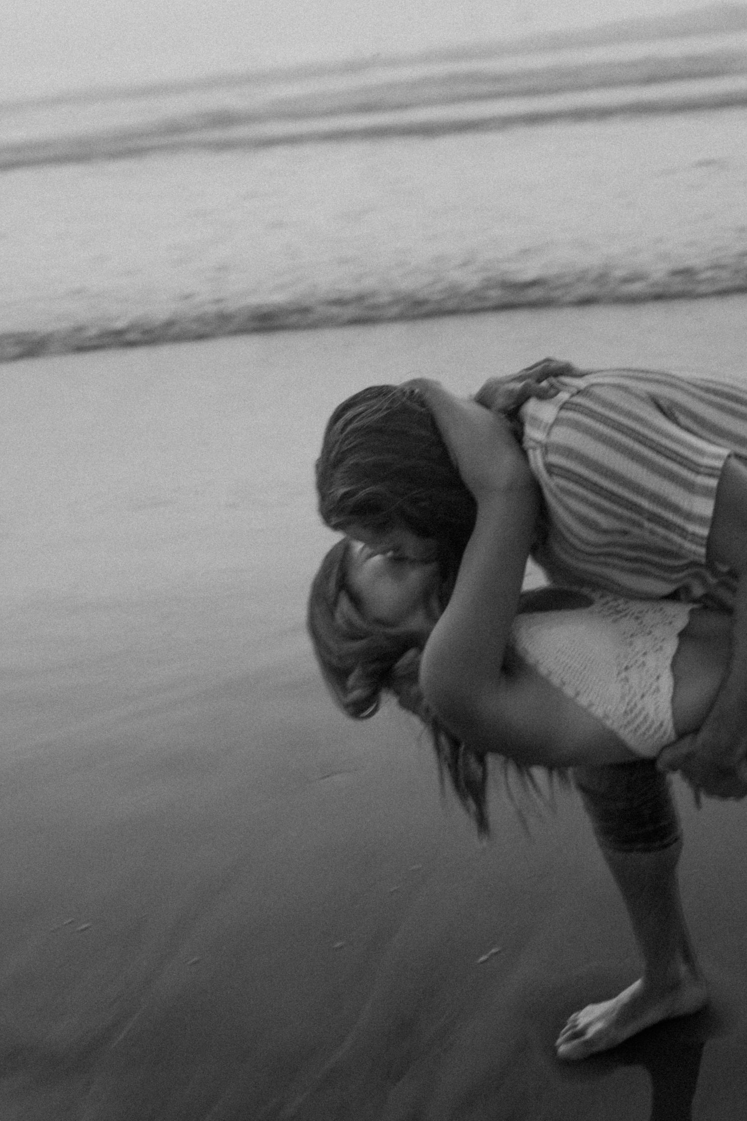 Playful black and white couples photo at the shoreline capturing intimate connection during a beach session.