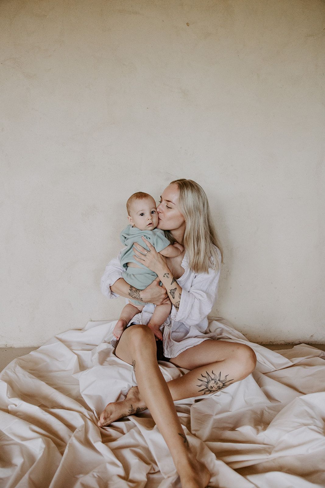 A tender moment between parent and baby captured in a series of intimate photos on white bedding.