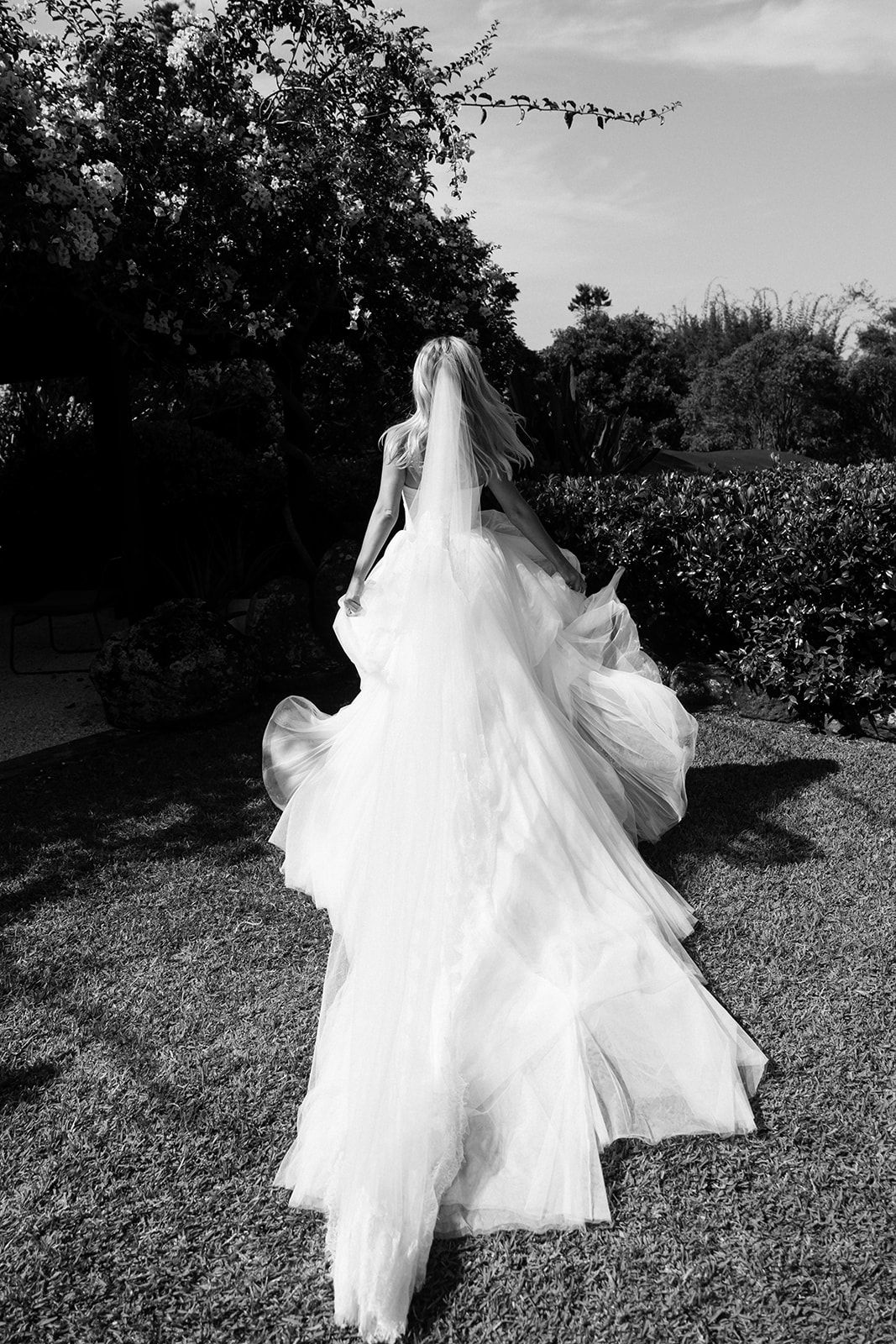 A dreamy black and white photo sequence shows a bride's flowing white wedding dress twirling in an outdoor garden setting.