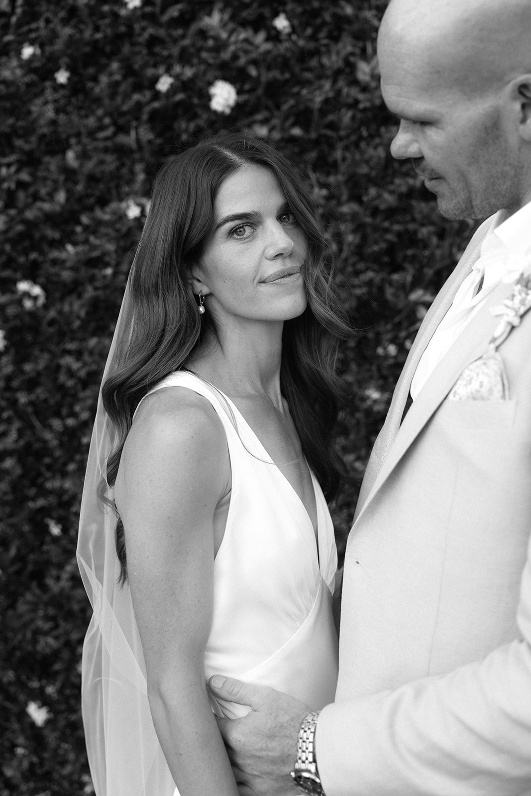 Black and white wedding portrait series showing romantic close-up moments between bride and groom against foliage backdrop.