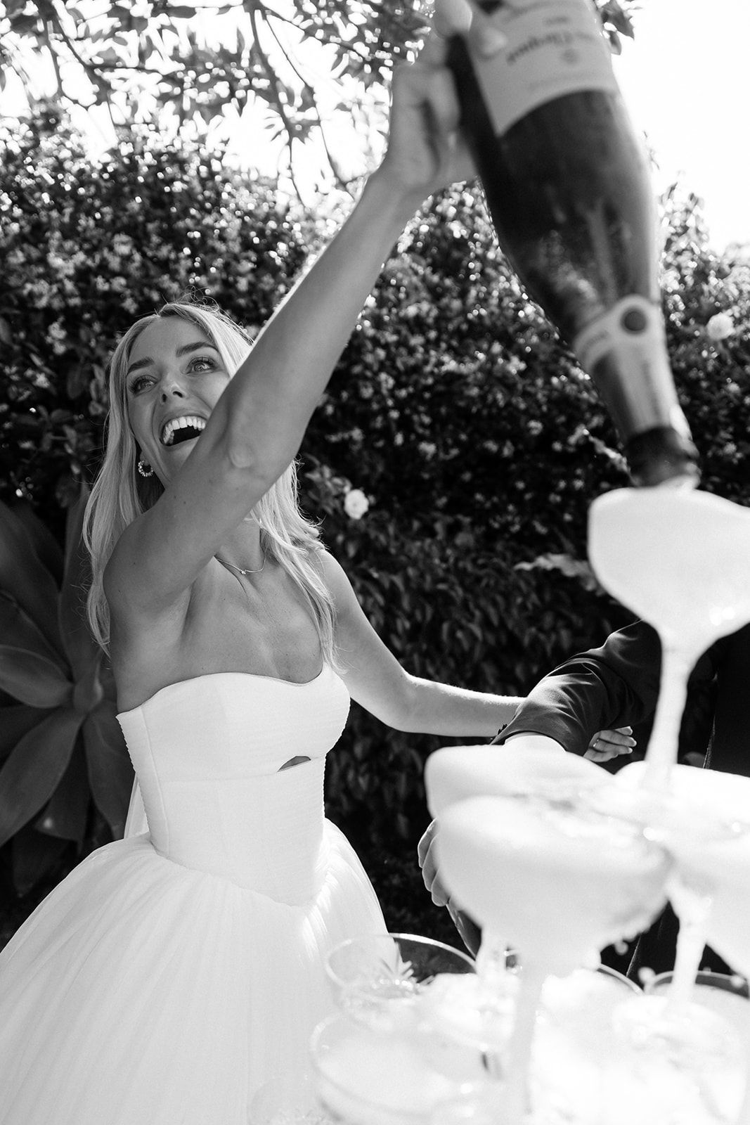 Series of black and white photos showing someone in a white wedding dress laughing joyfully at an outdoor celebration.