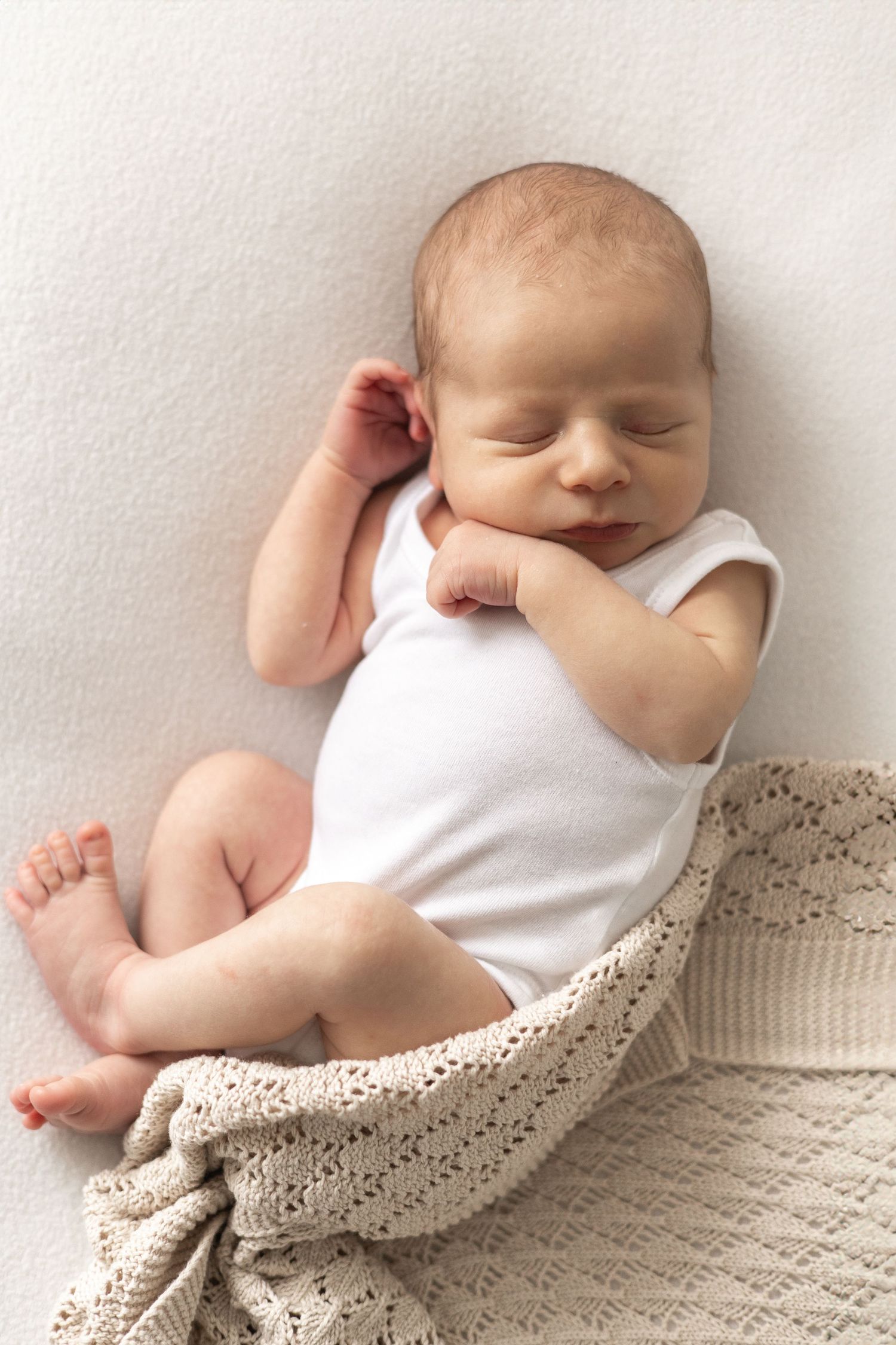 Newborn photoshoot Nottingham natural light baby portrait with blanket in cosy studio