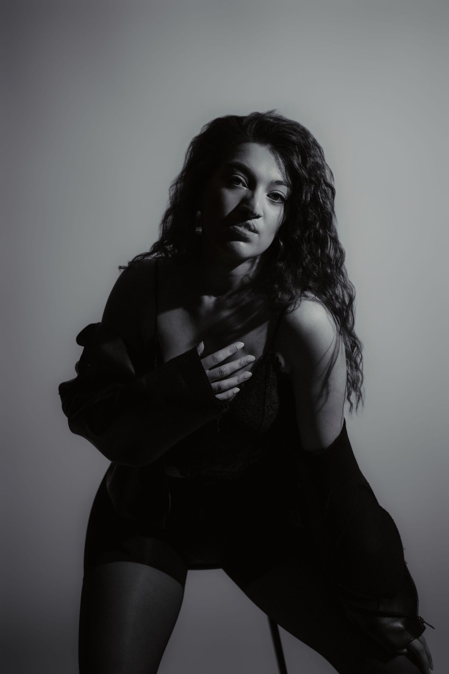 Portrait artistique en noir et blanc d'une femme éclairée par une lumière douce en studio.