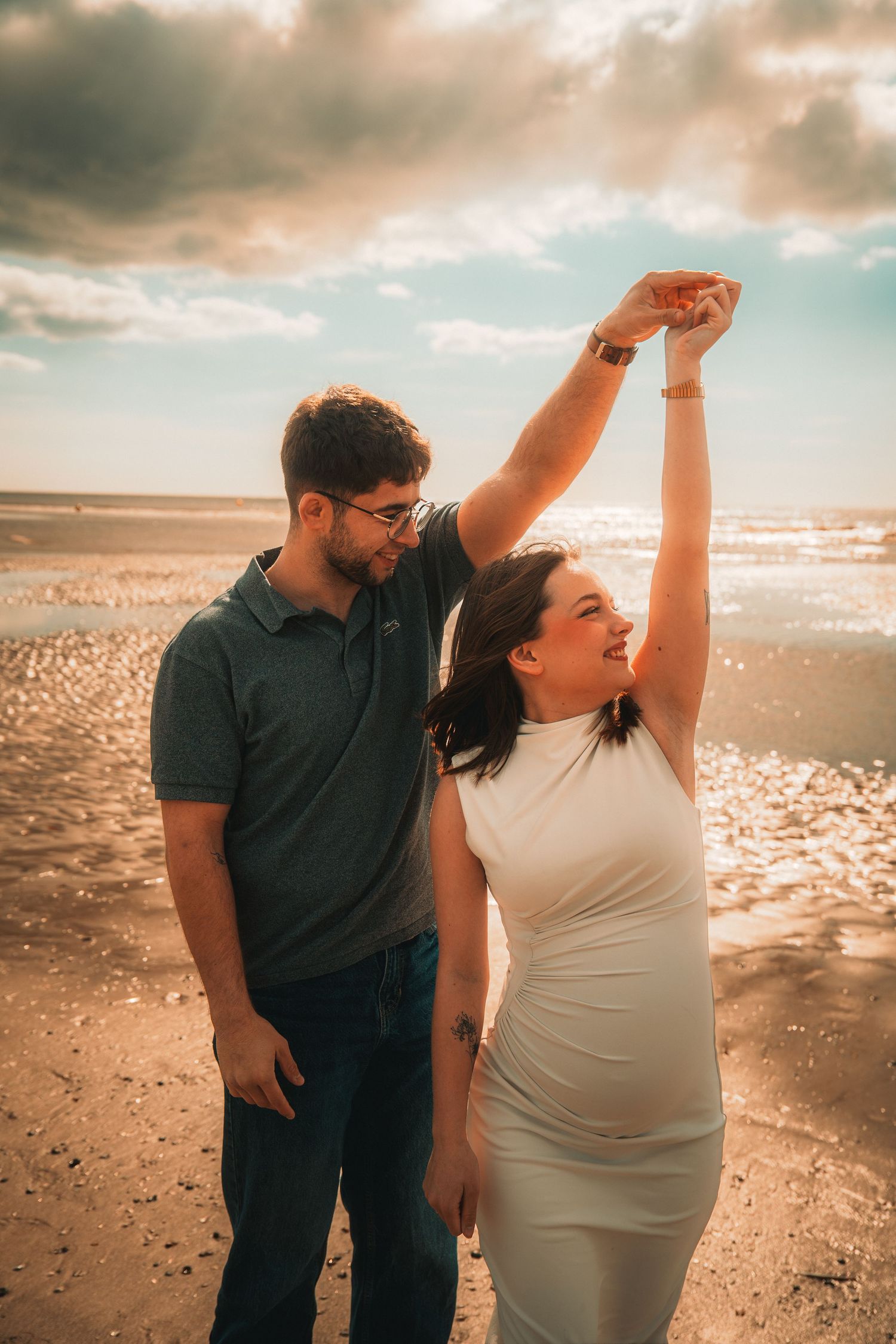Séance grossesse sur la plage au coucher du soleil capturant un moment de douceur et d'émotion.
