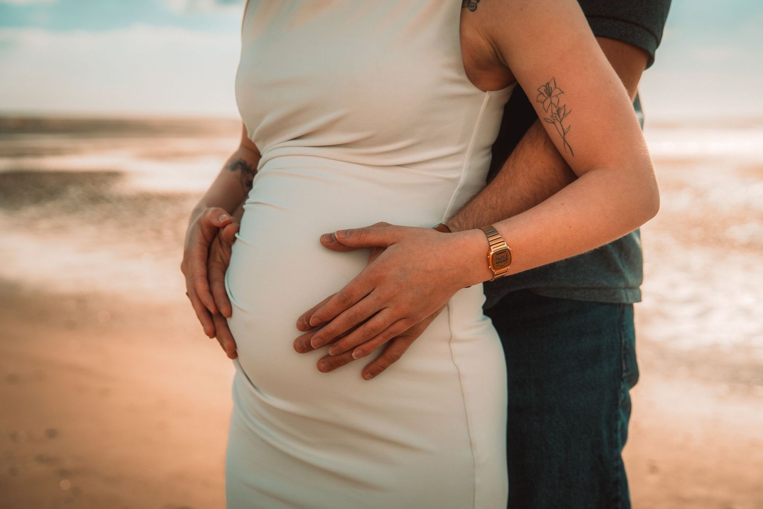 Séance photo de grossesse sur la plage immortalisant la complicité des futurs parents avant l'arrivée de leur enfant.