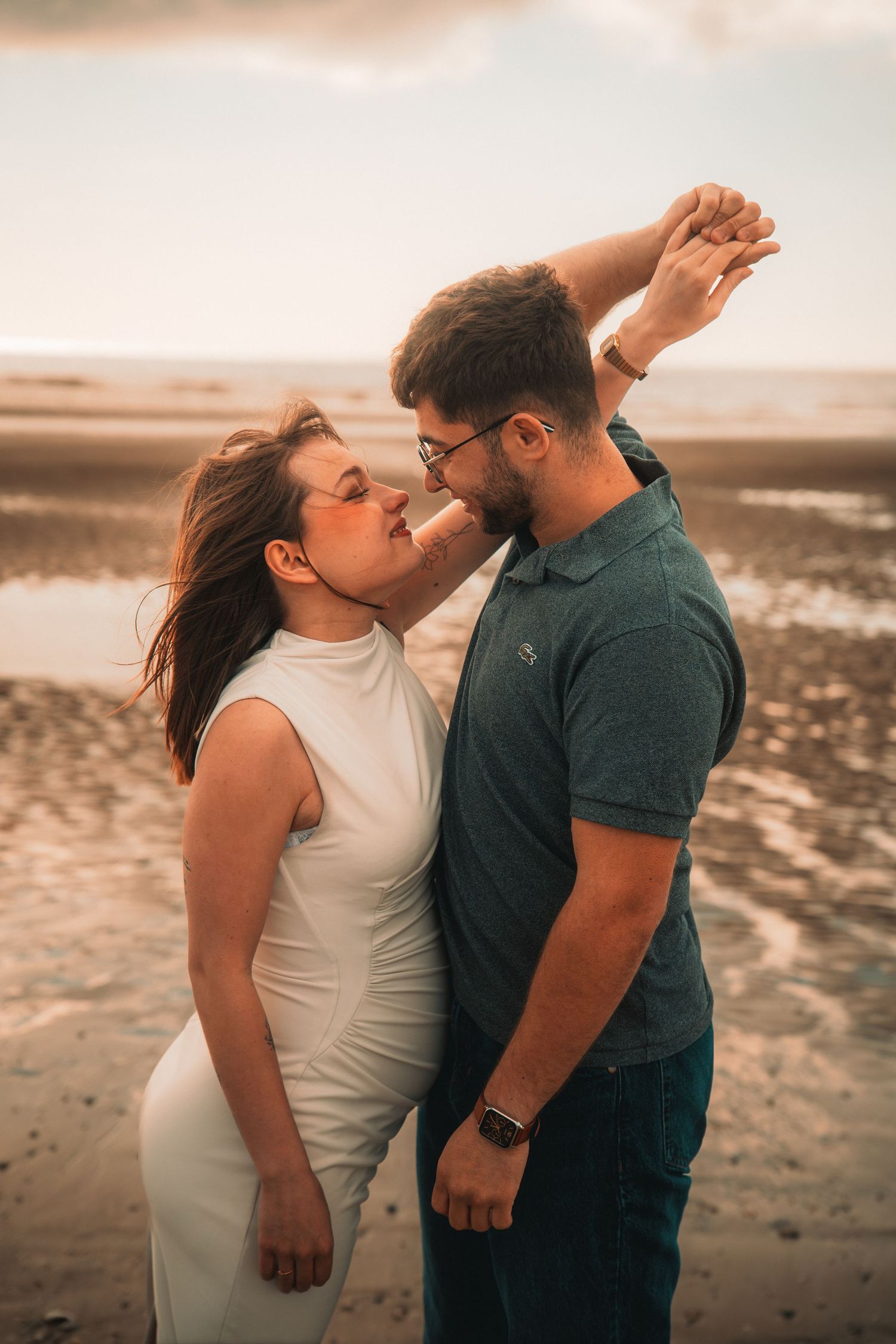Photographie de grossesse réalisée sur une plage avec une lumière douce et chaleureuse.