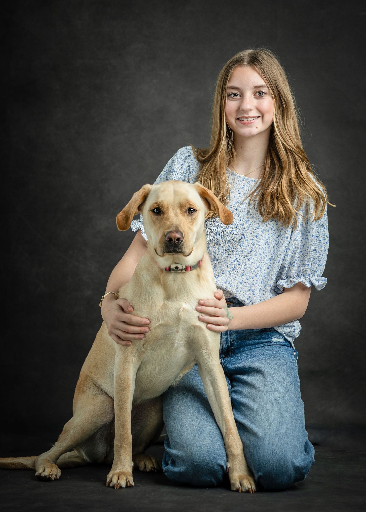 Yellow Labrador puppy and owner studio portraits with dark background.