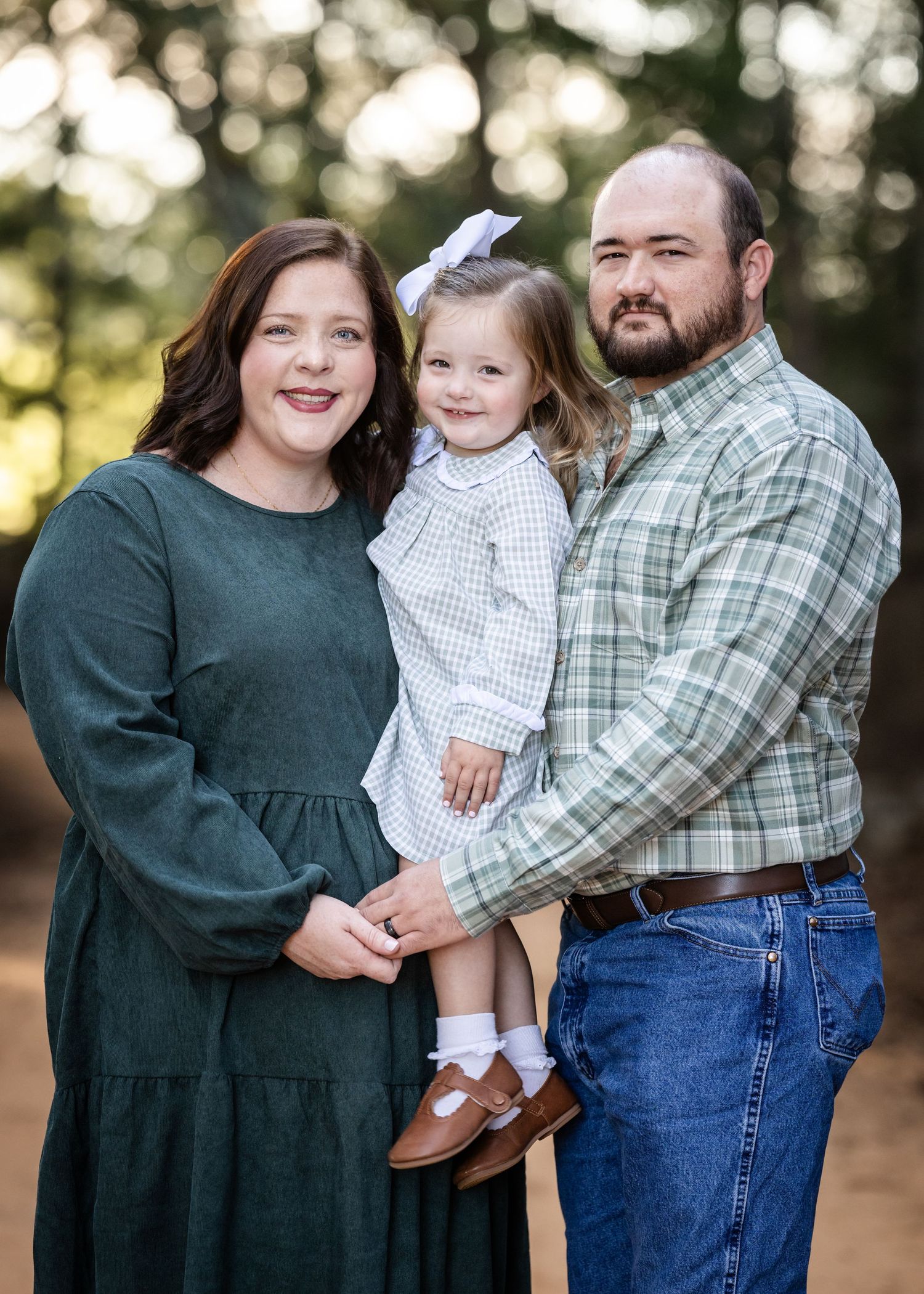 Family in green and plaid outfits posing together outdoors for a portrait.